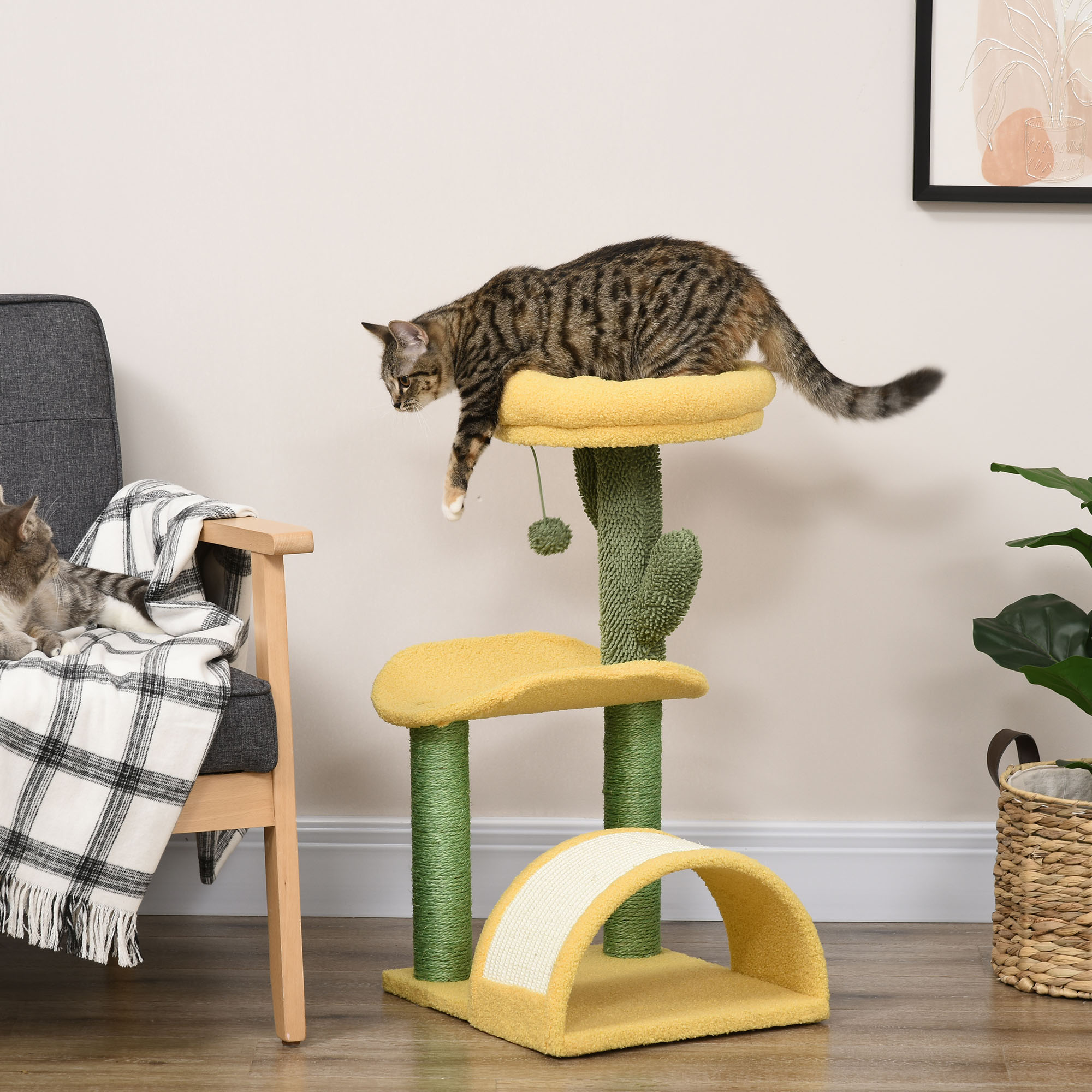 Un gato salta desde la cima de un árbol para gatos amarillo. Otro gato se sienta en una silla. Hay una planta y una alfombra.