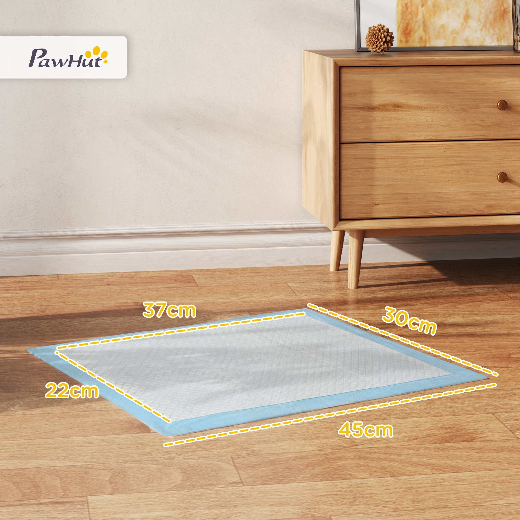 Almohadilla absorbente azul para mascotas en un piso de madera. Se indican las dimensiones. Un gabinete marrón claro está en el fondo.