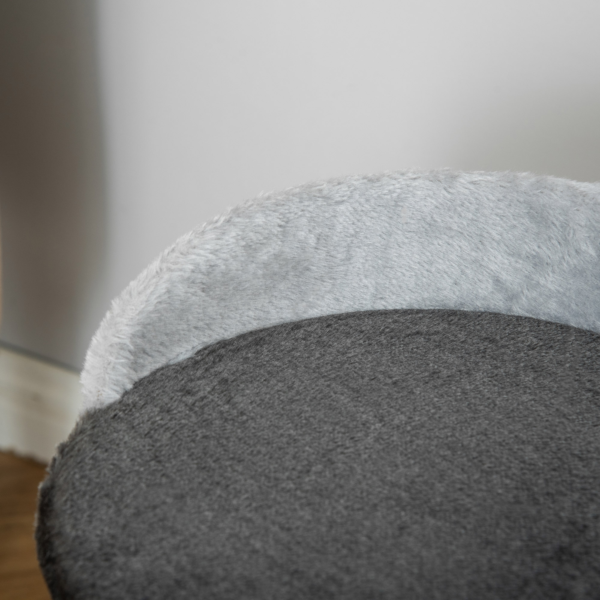 Primer plano de una cama gris para mascotas, la parte superior es esponjosa, la inferior es más oscura.