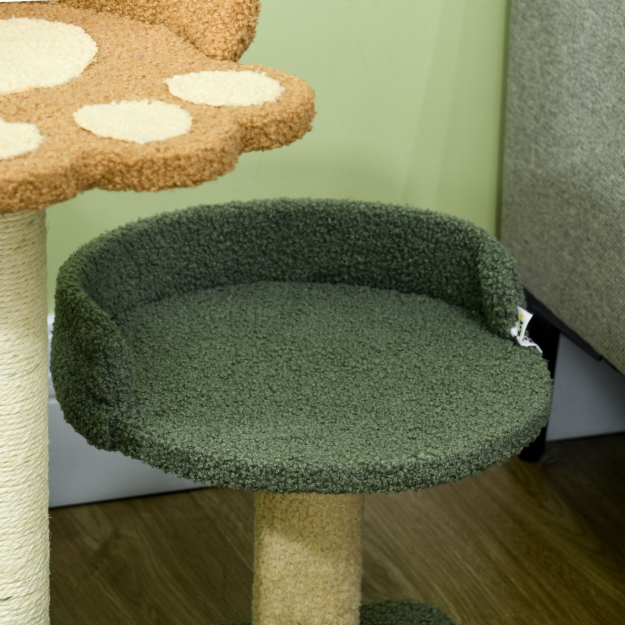 Primer plano de una percha de árbol para gatos. La percha es verde y tiene una textura esponjosa. El marco es beige.