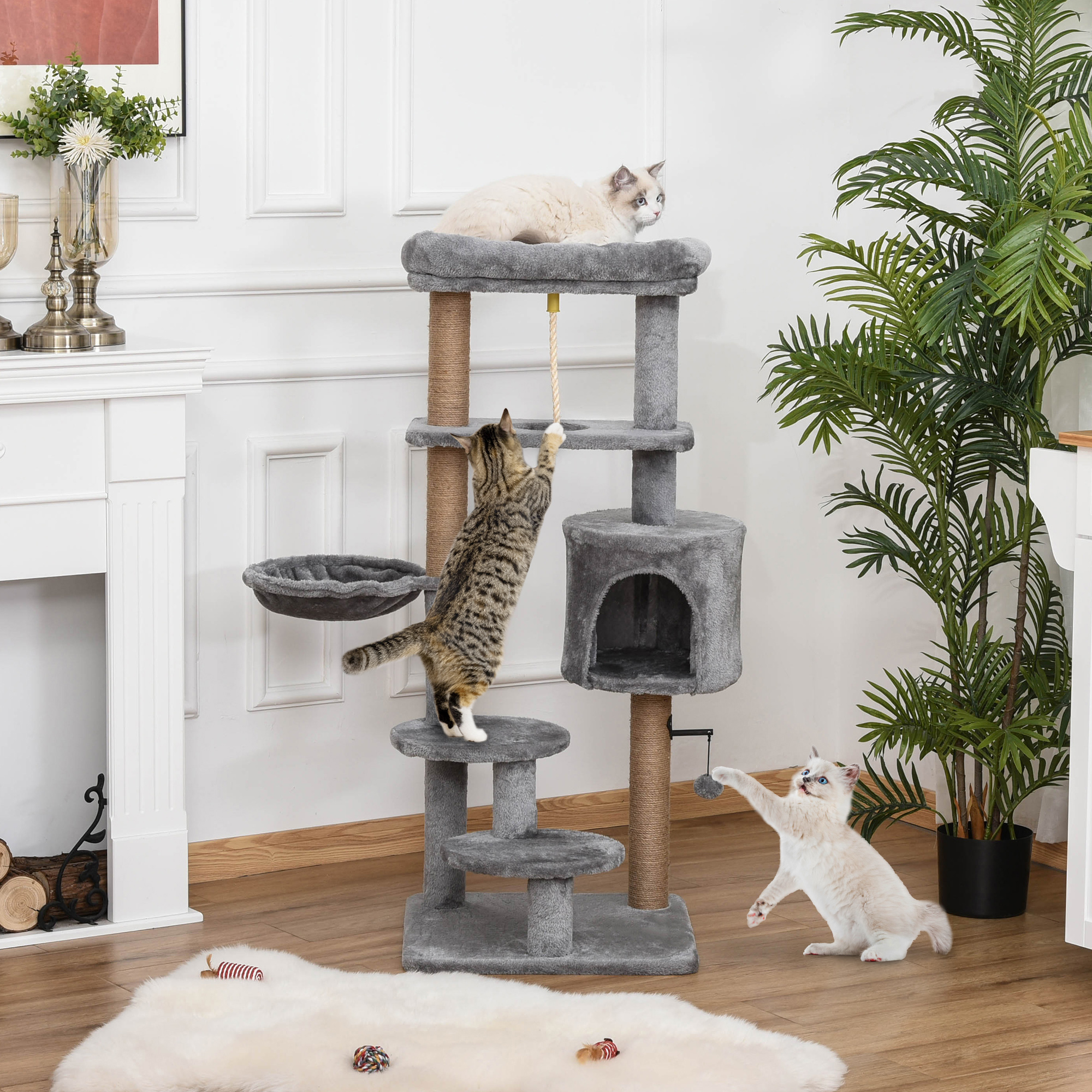 Gatos jugando en un árbol para gatos de varios niveles.