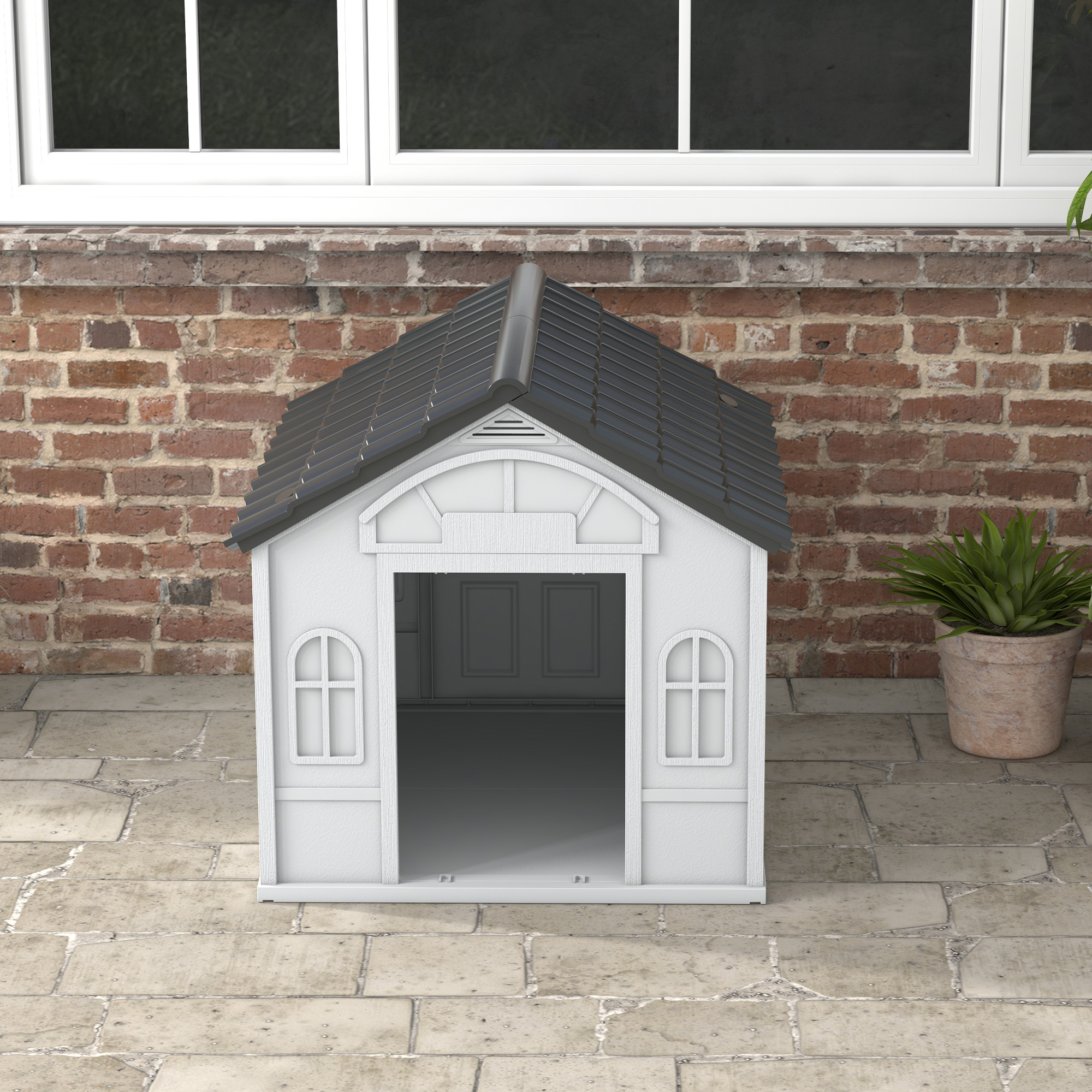 Casa para perros blanca y gris con techo negro. Situada en un patio de ladrillo y piedra.