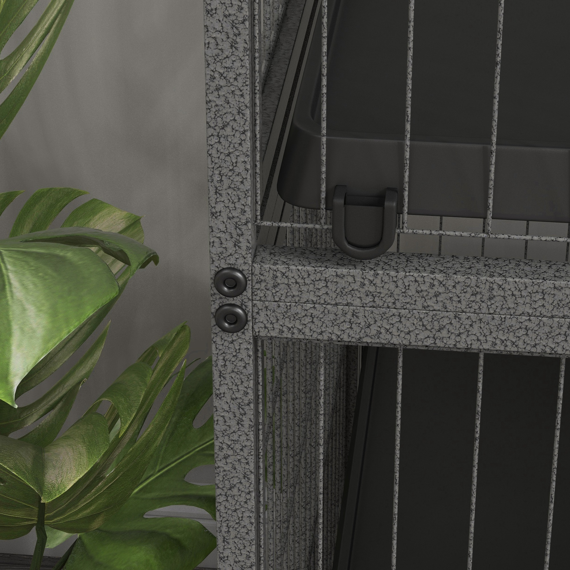Un primer plano de una jaula gris con elementos negros. Hay una planta en el fondo.