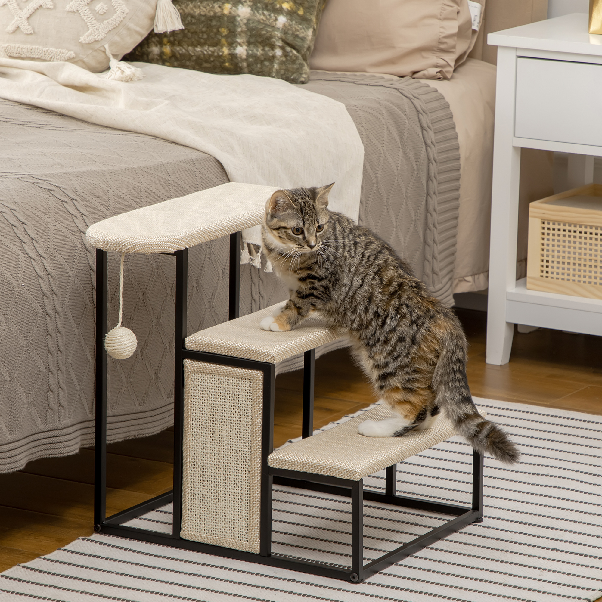 Un gato subiendo una escalera para gatos, con superficie beige, marco negro y un juguete. El fondo muestra una cama.