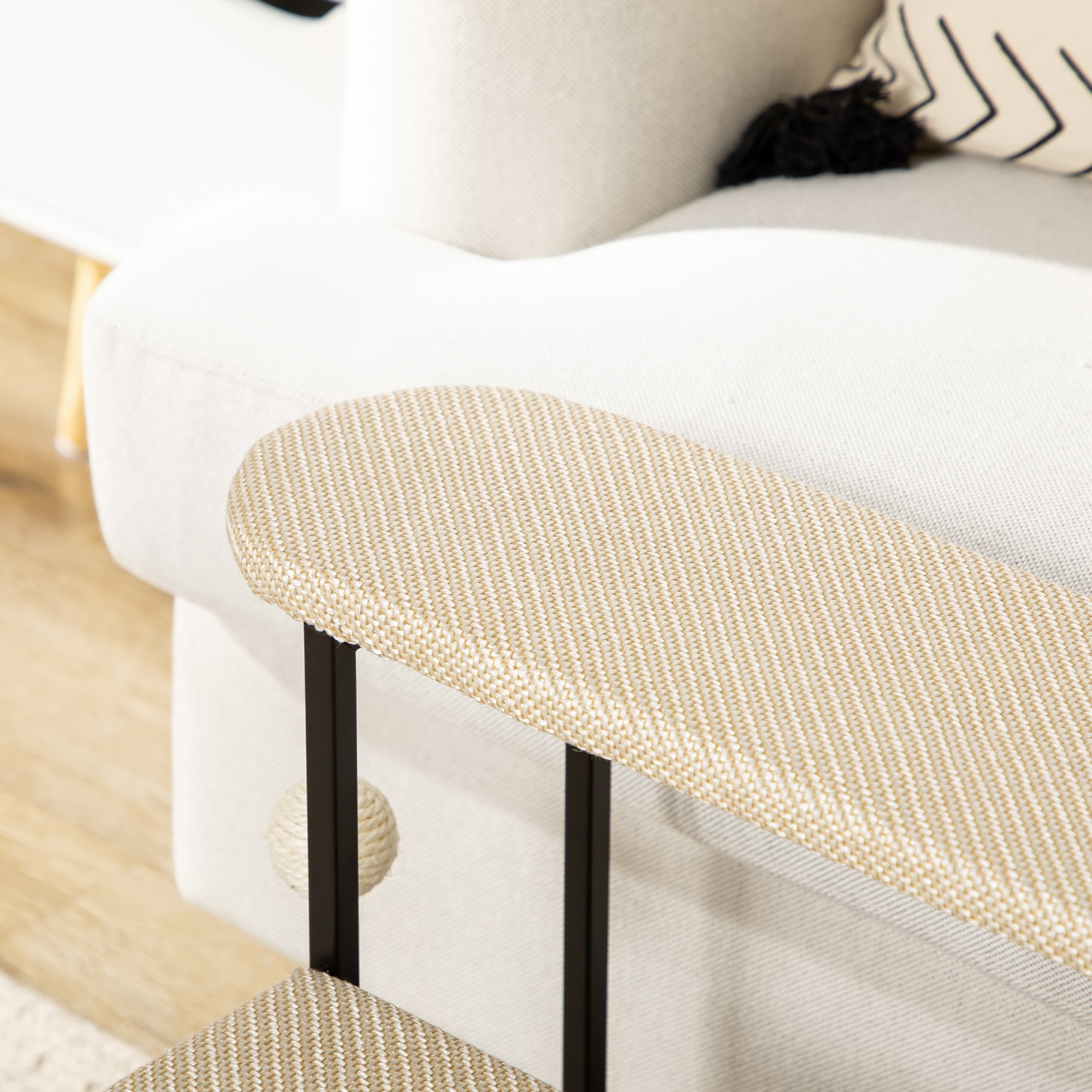 Primer plano del reposabrazos de un árbol para gatos. Es beige con soportes de metal negro y una bola.