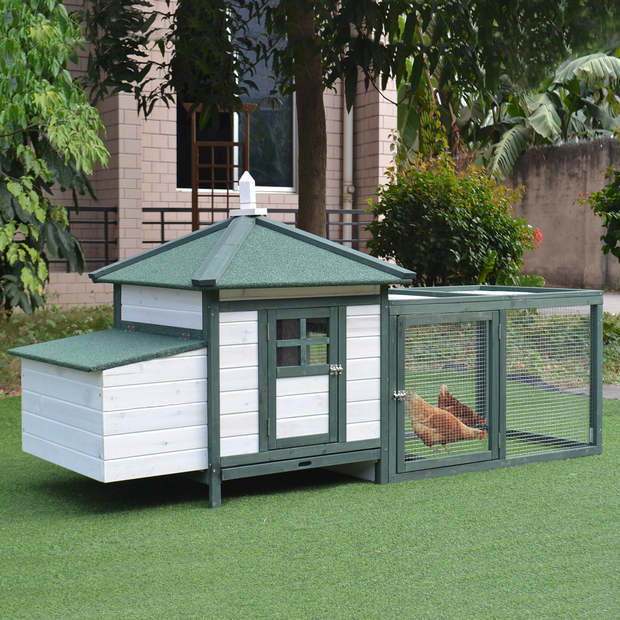 Un gallinero de madera blanco y verde sobre un césped verde. Dos gallinas están dentro del gallinero.