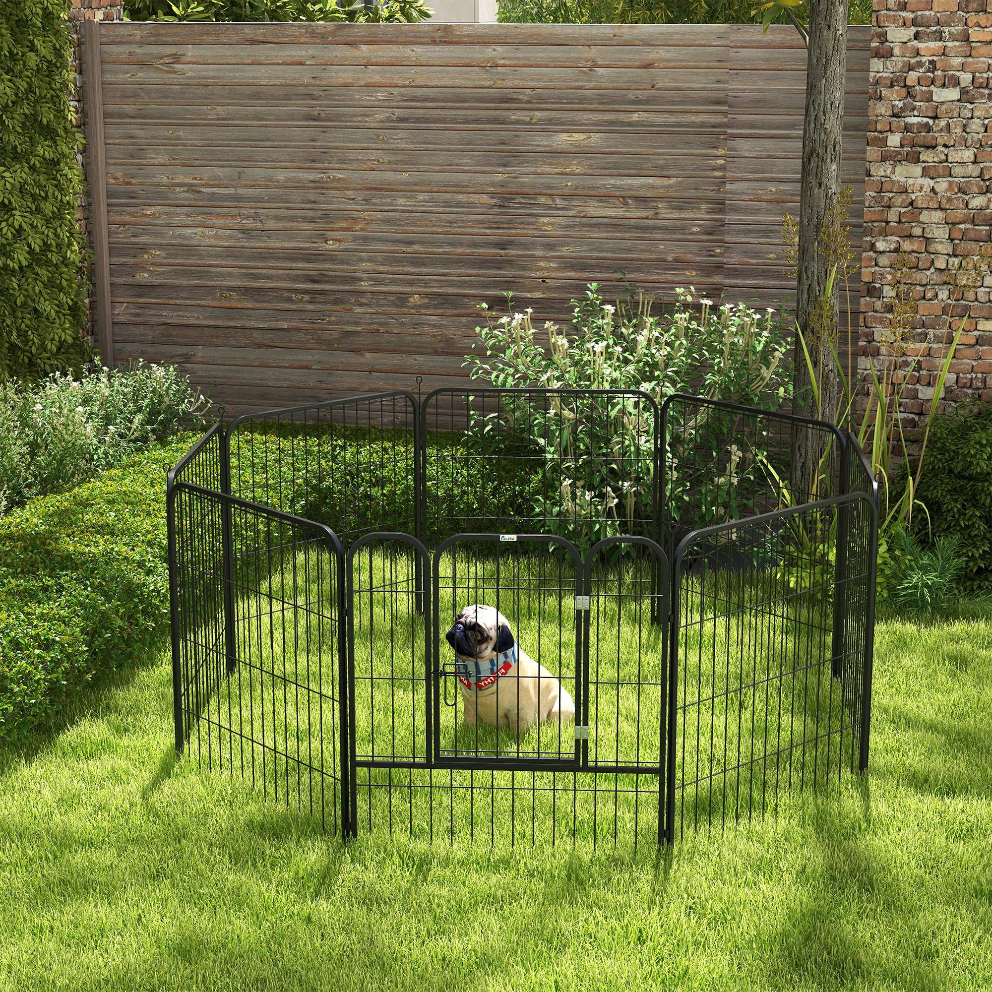 Parque para perros de malla de alambre negro. Un pug está dentro, en un jardín con césped. Valla al fondo.