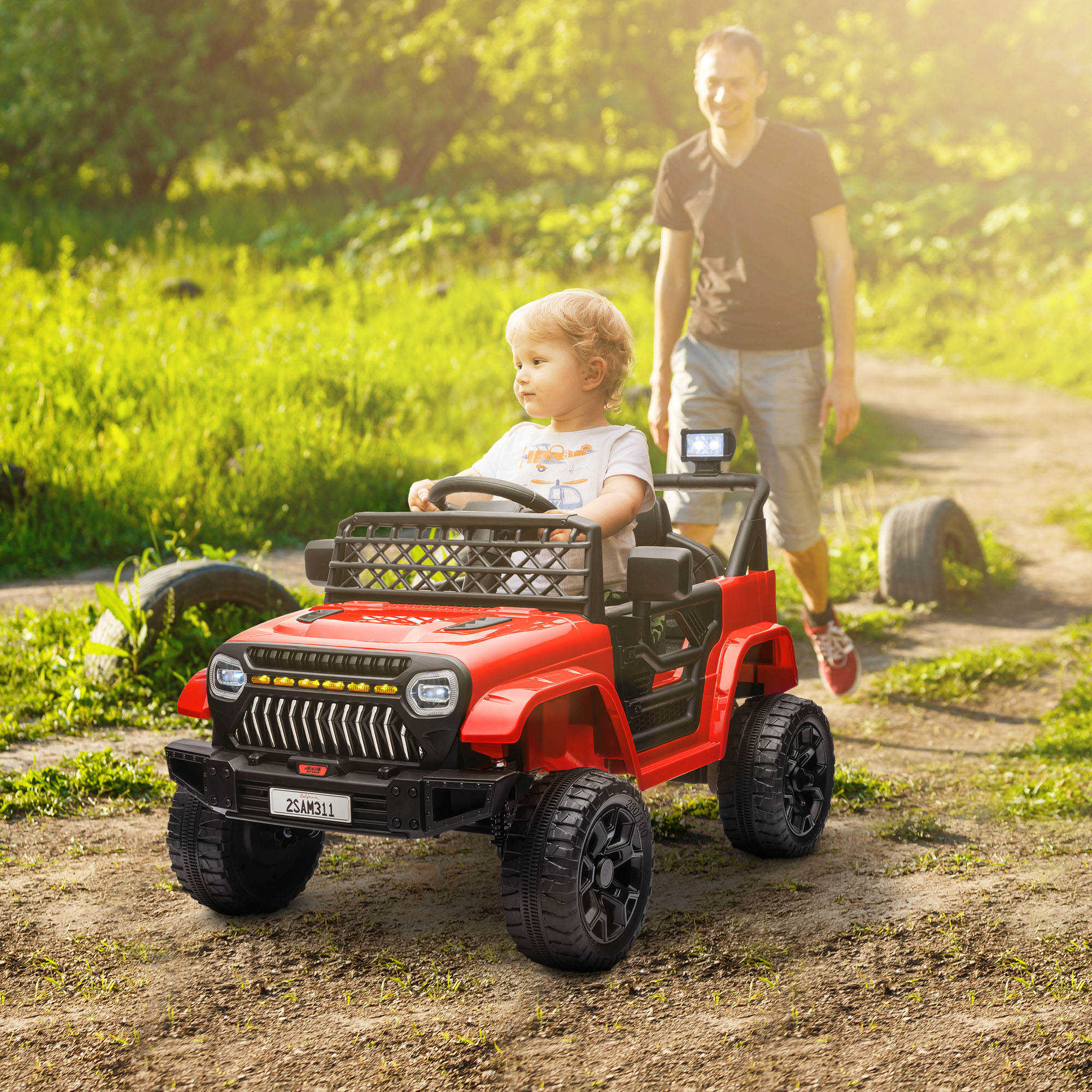 Un niño conduce un jeep de juguete rojo en un camino de tierra, con un adulto caminando detrás.