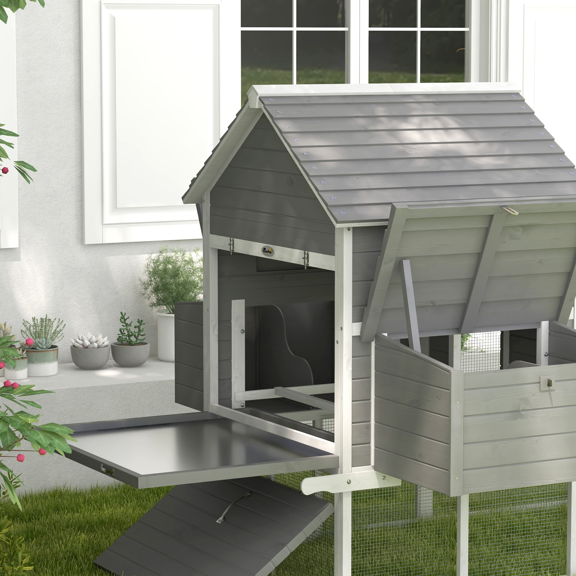 Primer plano de un gallinero gris y blanco con la puerta abierta.