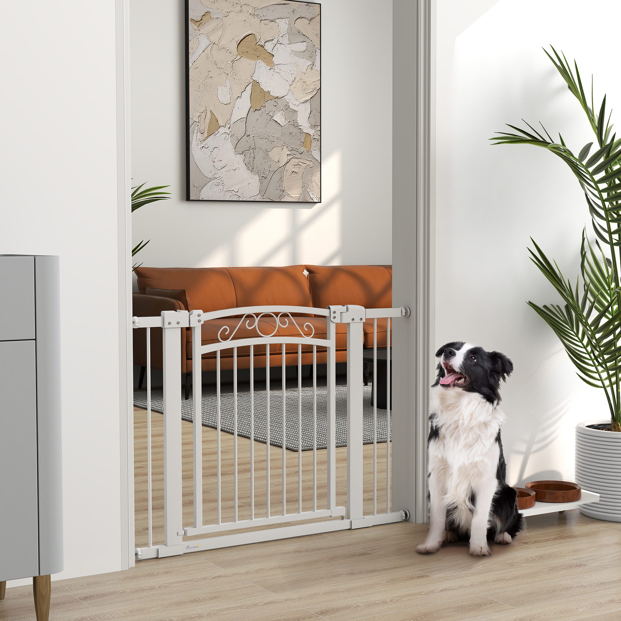 Un perro blanco sentado junto a una puerta. Detrás hay un salón con sofá marrón y pintura.