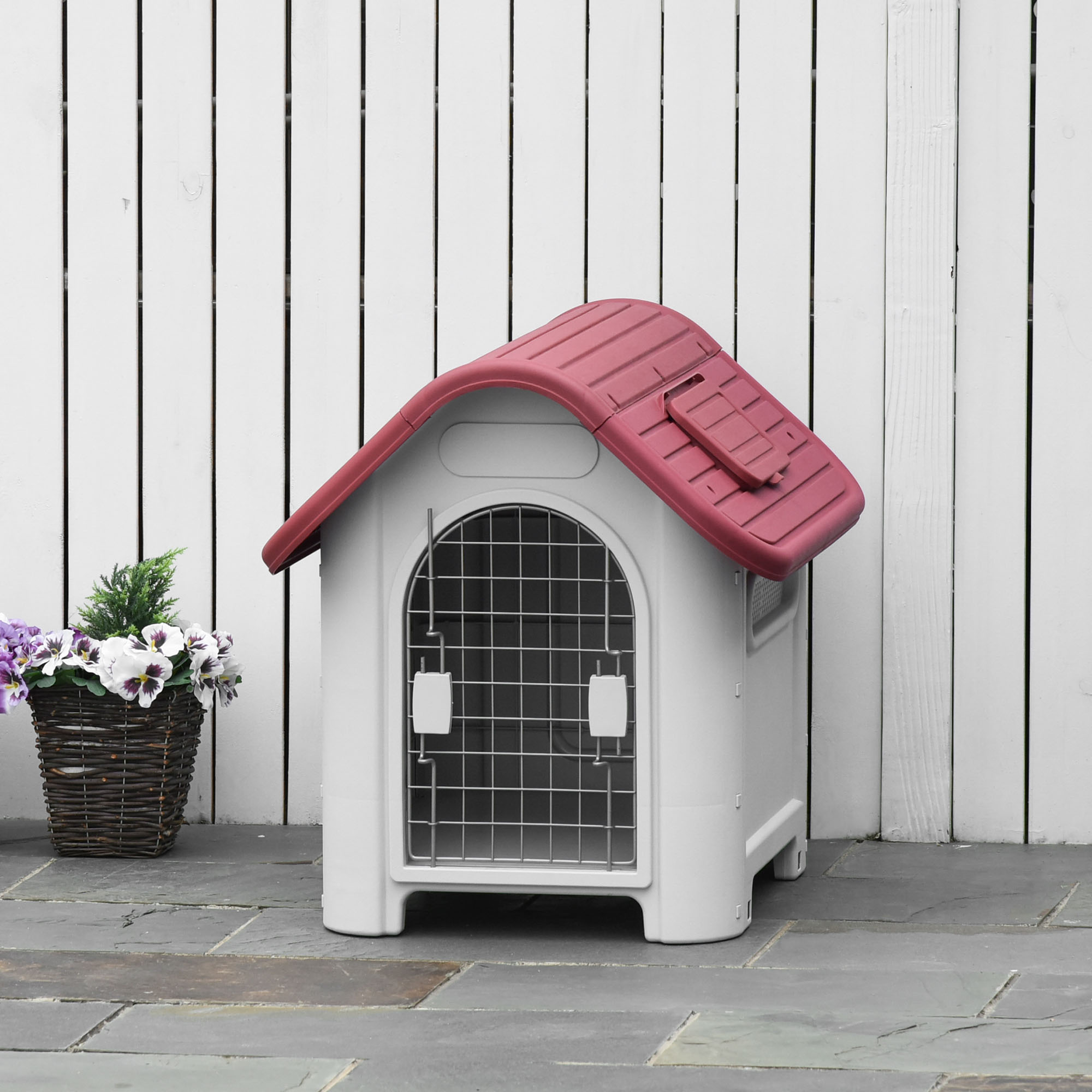 Casa para perros blanca y roja. La casa tiene un techo rojo y una puerta de alambre.