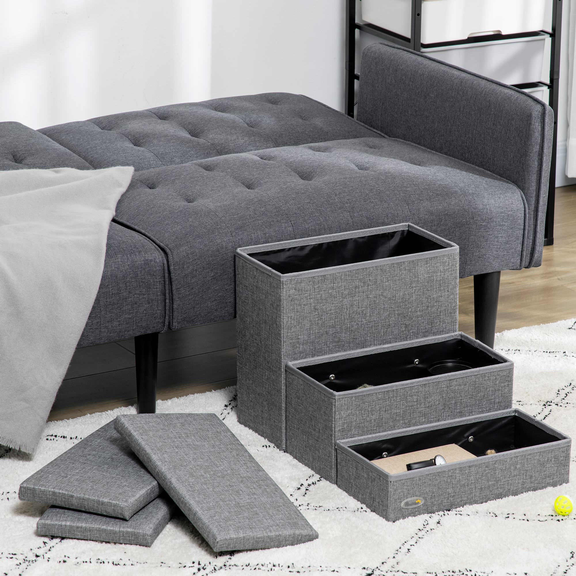 Sofá seccional gris con cajas de almacenamiento grises y cubiertas sobre una alfombra blanca estampada.