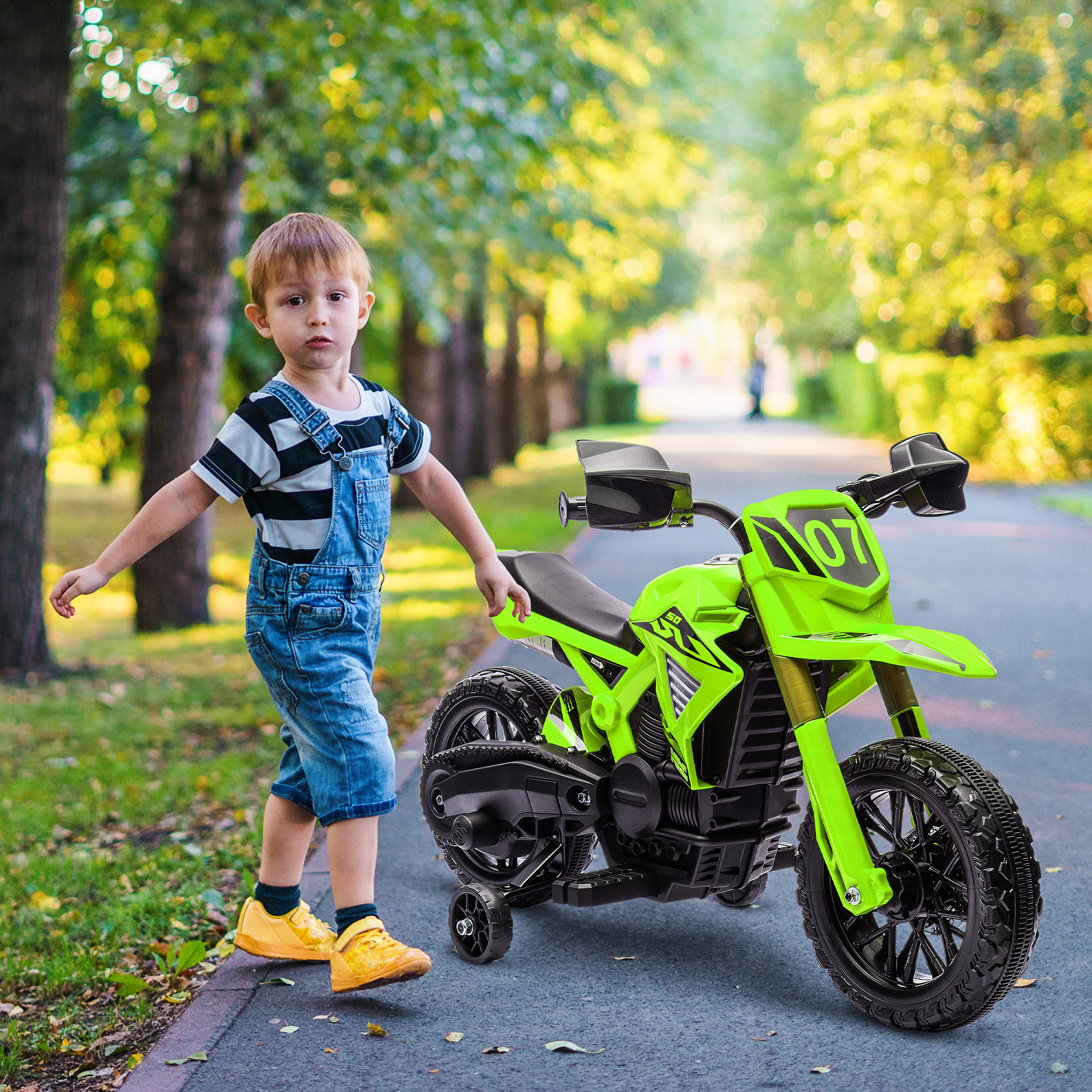 Un niño y una motocicleta verde en un camino pavimentado con árboles. Fondo: un camino verde con árboles.
