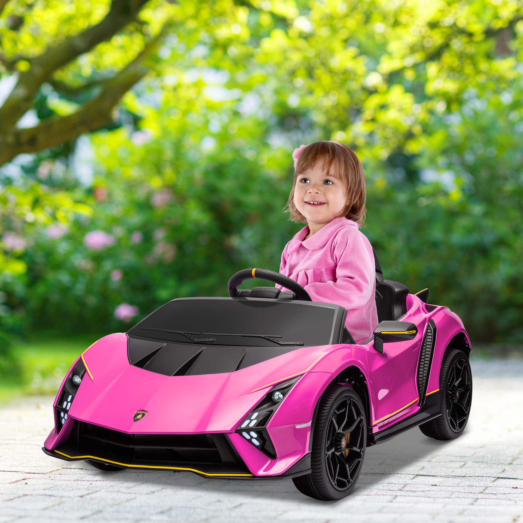 Una niña en un coche de juguete rosa. El coche es rosa y tiene neumáticos negros. El fondo es un jardín verde.
