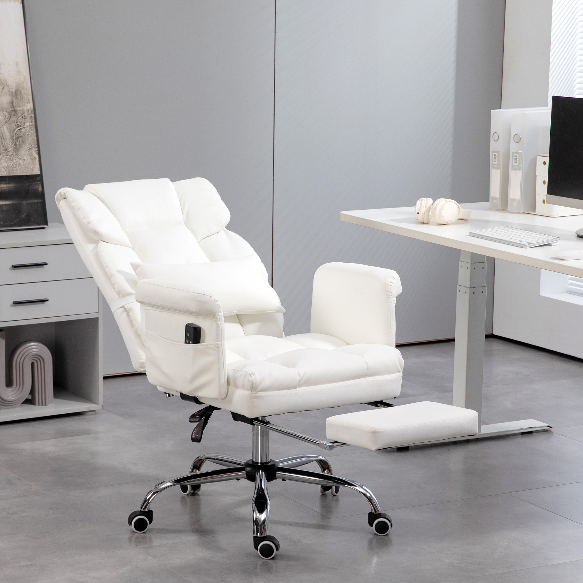 Una silla de oficina de cuero blanco con reposapiés y un escritorio al fondo.