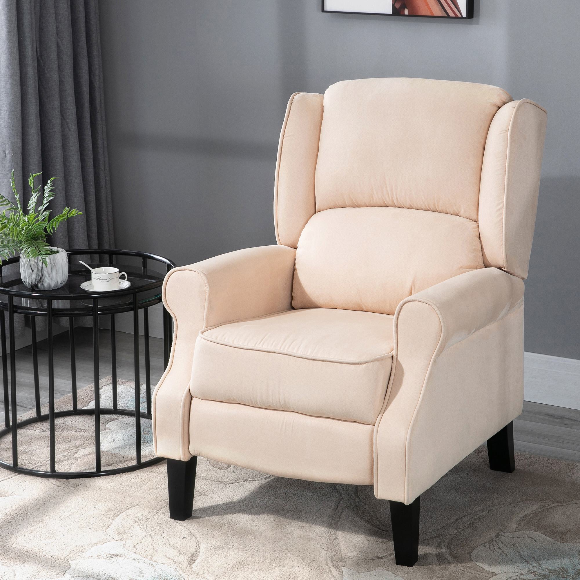 Sillón reclinable beige. Una mesa auxiliar negra con una planta y una taza de café.