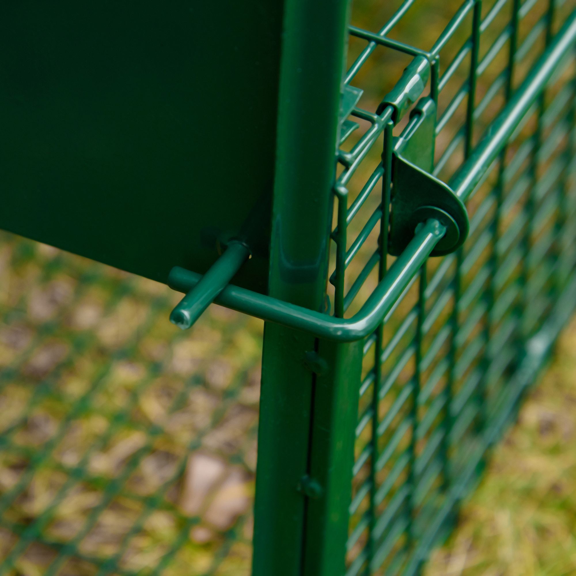 Un detalle de una valla metálica verde, que muestra la conexión de los elementos.
