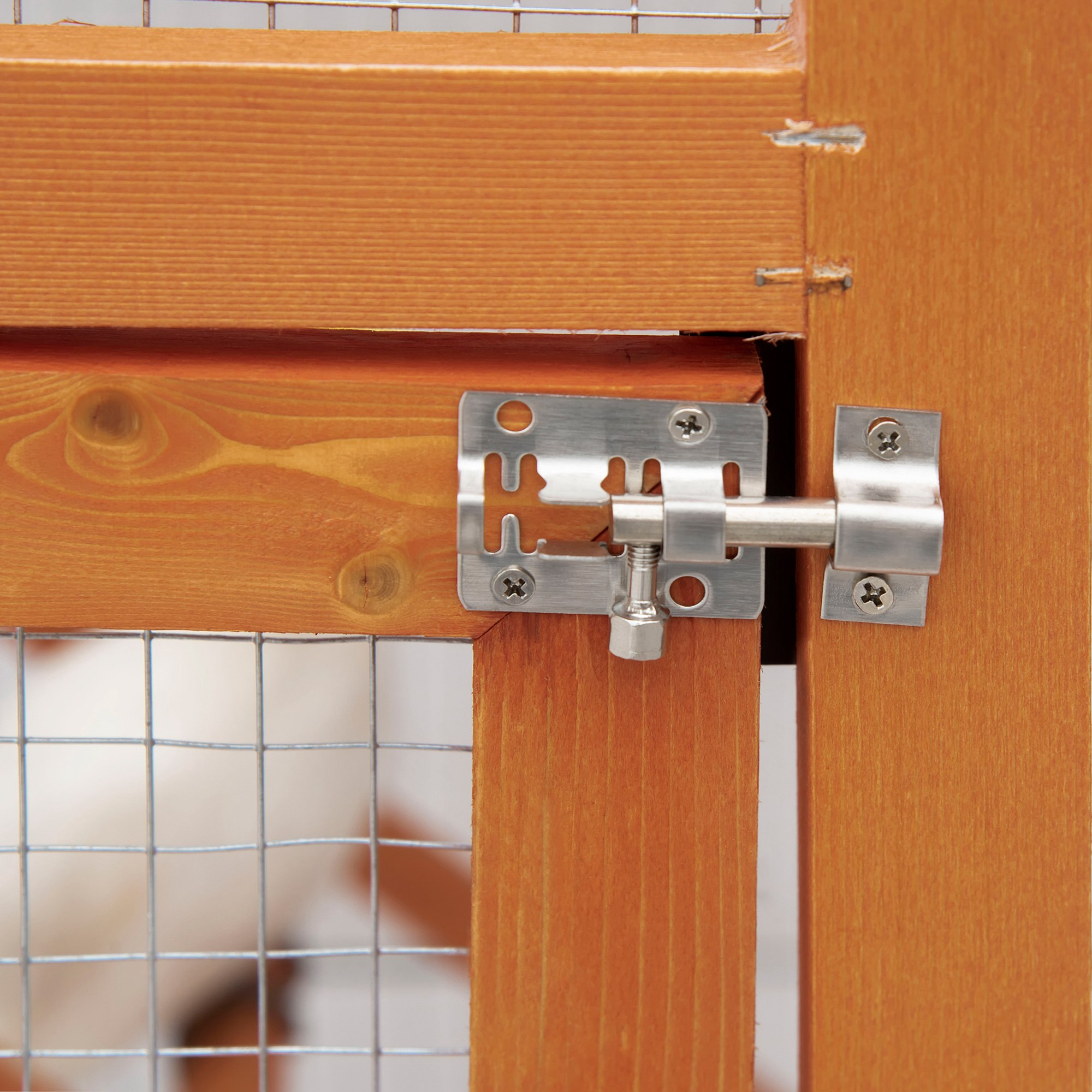 Primer plano del pestillo de una puerta de casa para mascotas. El pestillo es metálico, sobre un marco de puerta de madera.