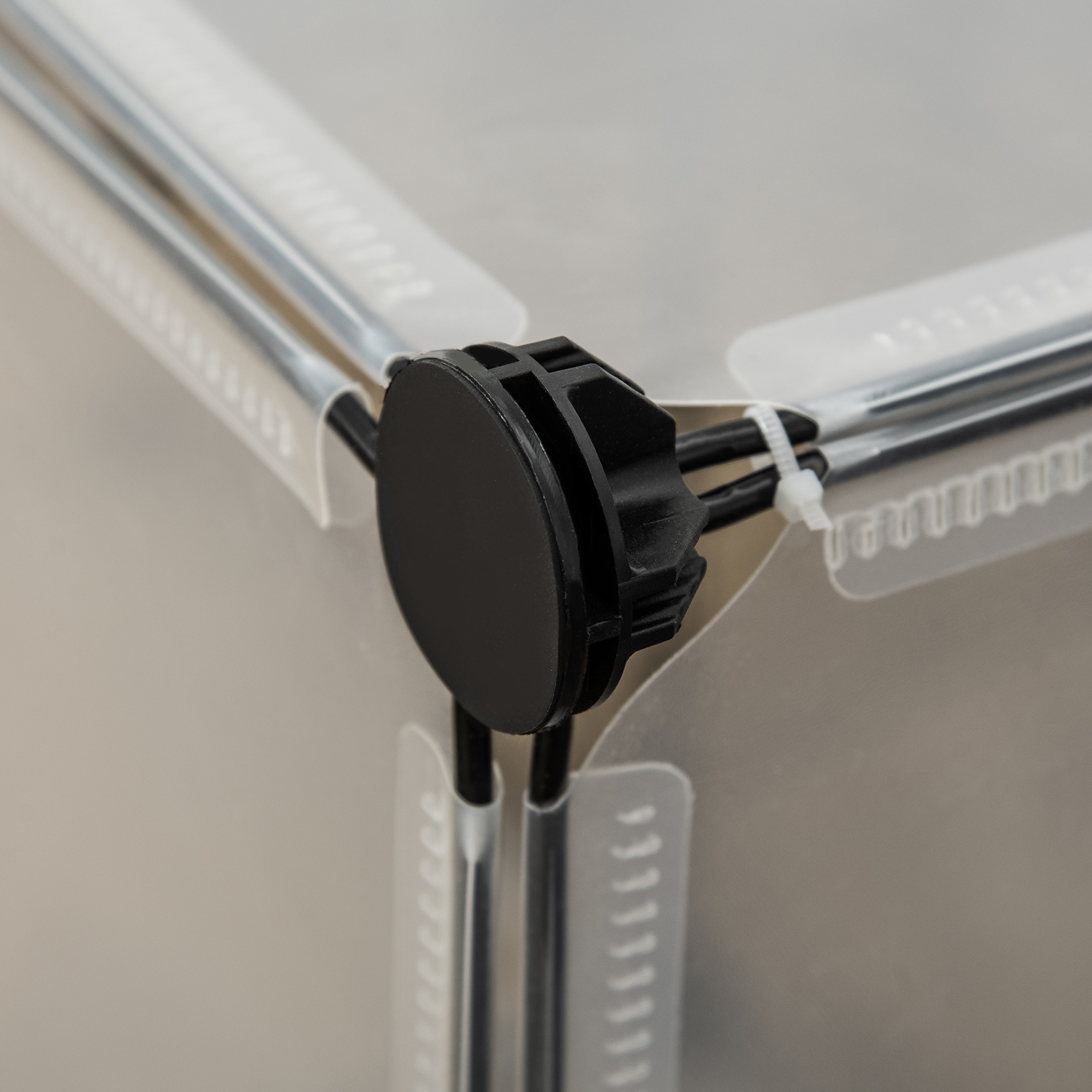 Primer plano de un conector de plástico negro, conectando las esquinas de paneles de plástico transparente.