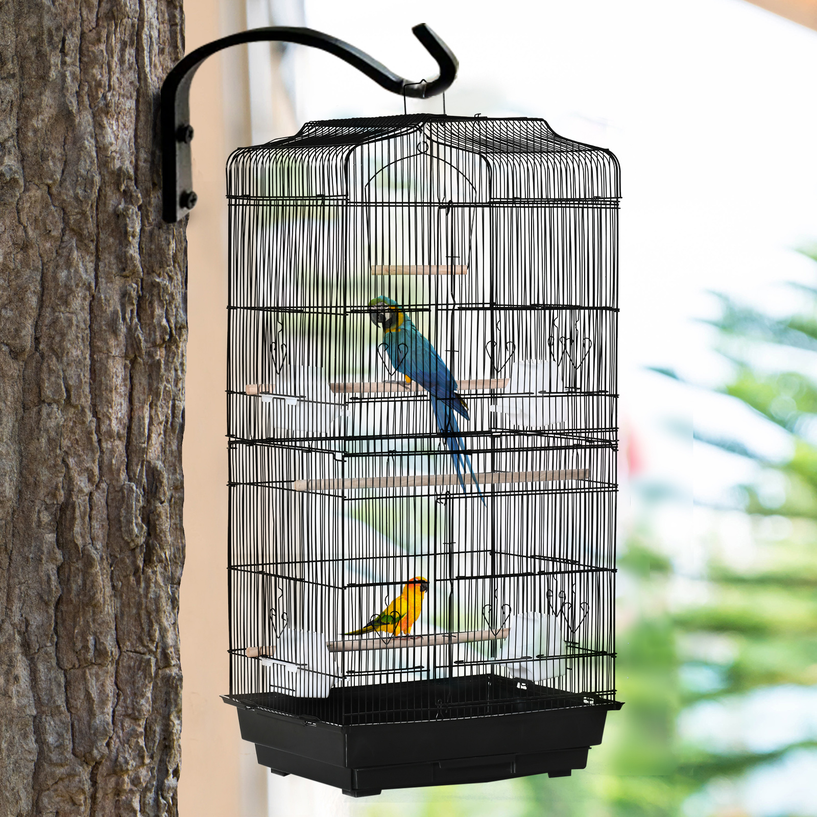 Jaula negra para pájaros colgada de un árbol. Dos pájaros, uno azul y amarillo, otro amarillo, están dentro.