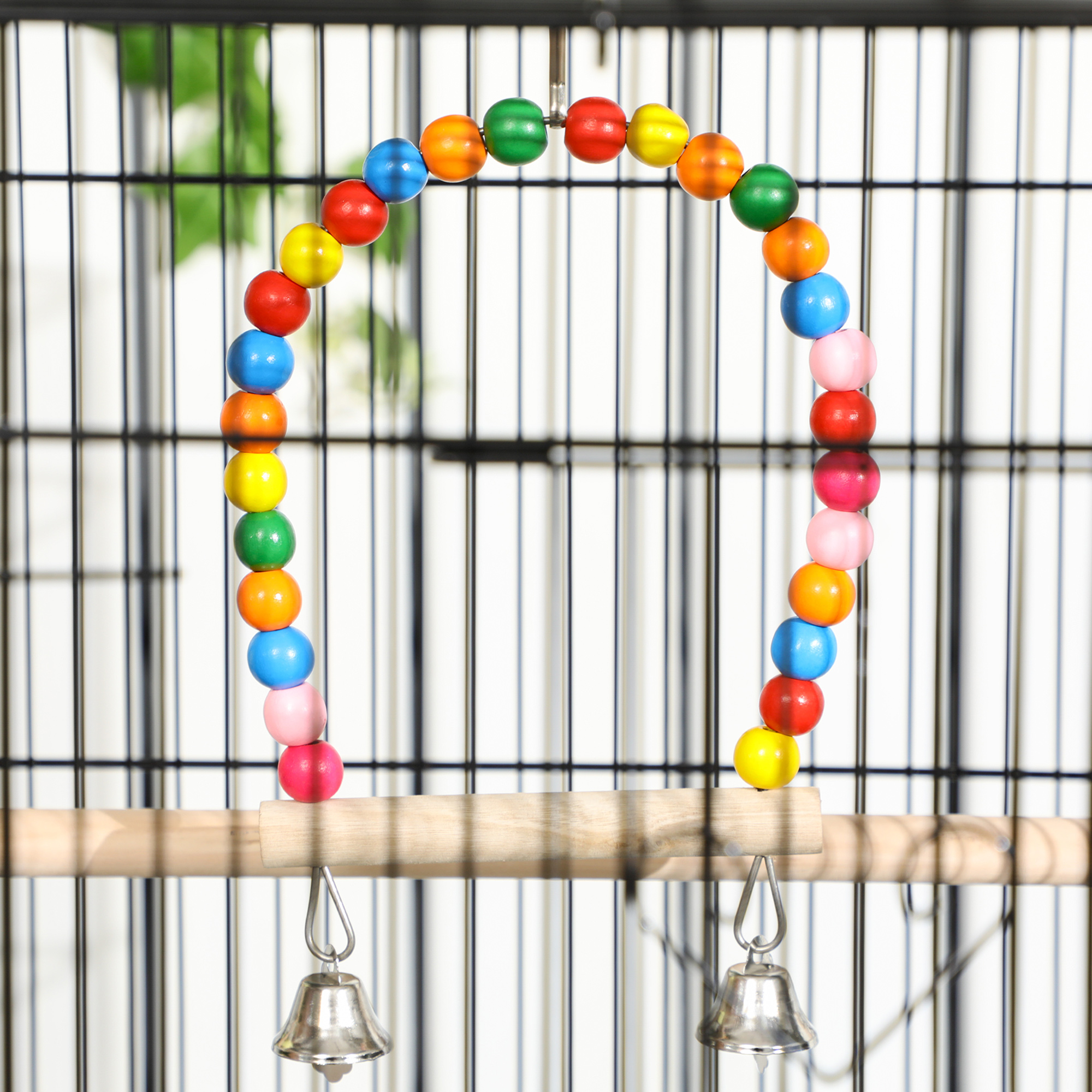 Un colorido juguete para pájaros con campanas colgando en una jaula.