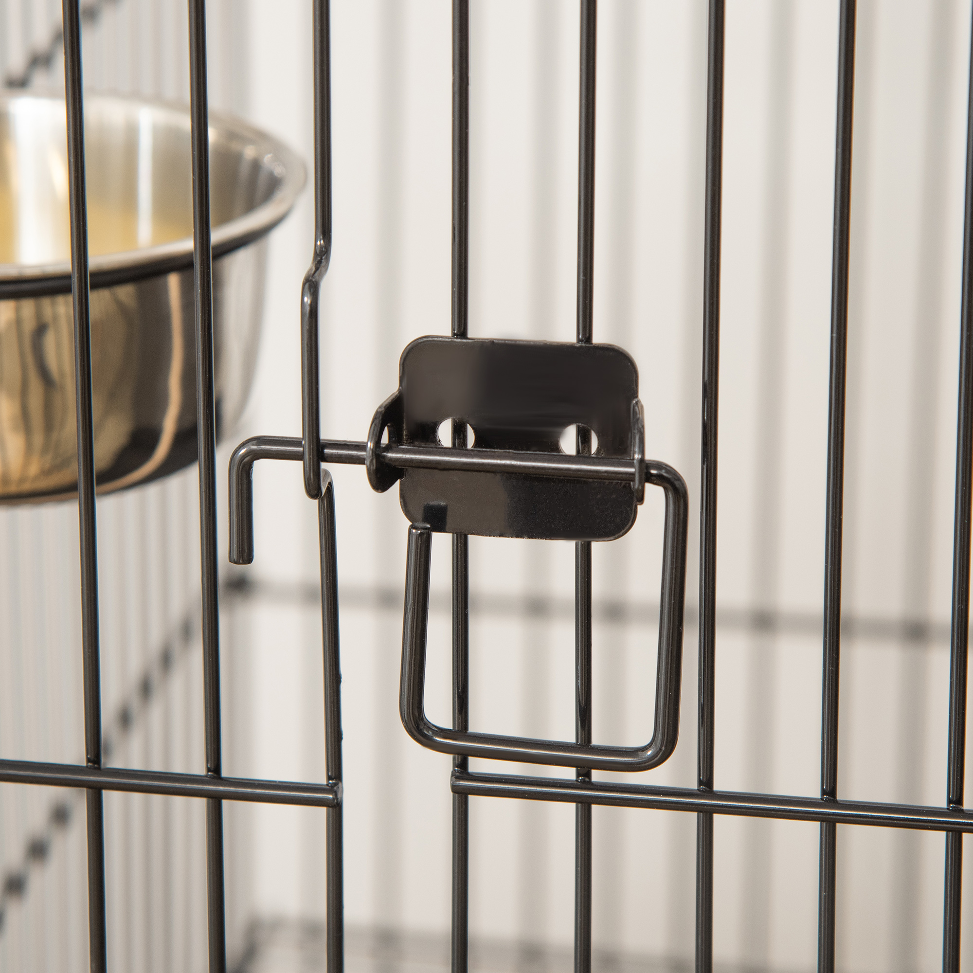 Primer plano del pestillo de la puerta de una jaula de metal negro. El pestillo es un diseño simple de gancho y bucle.