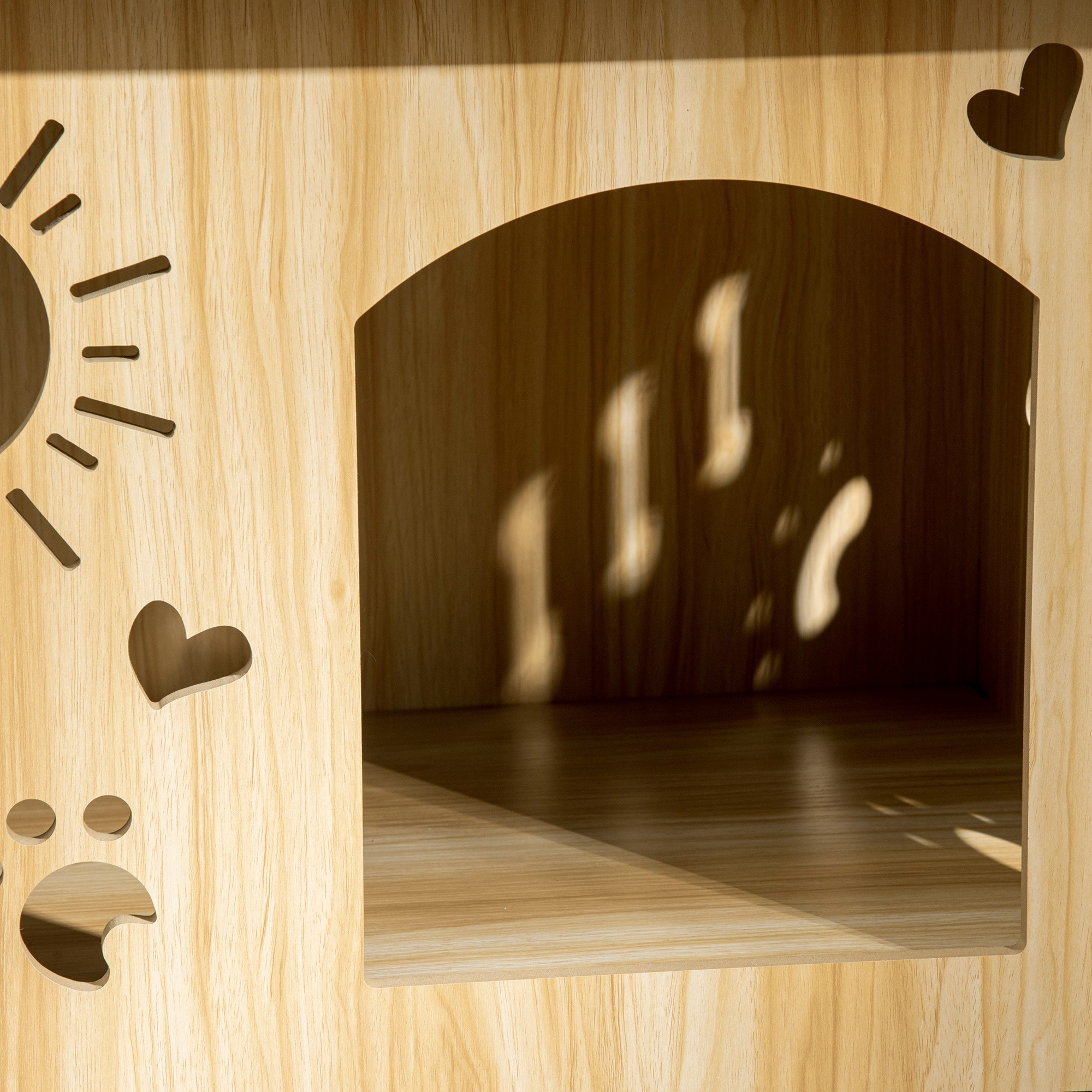 Casa para gatos de madera con recortes de corazón y sol. El interior de la casa es visible. La casa está sobre un fondo de madera.