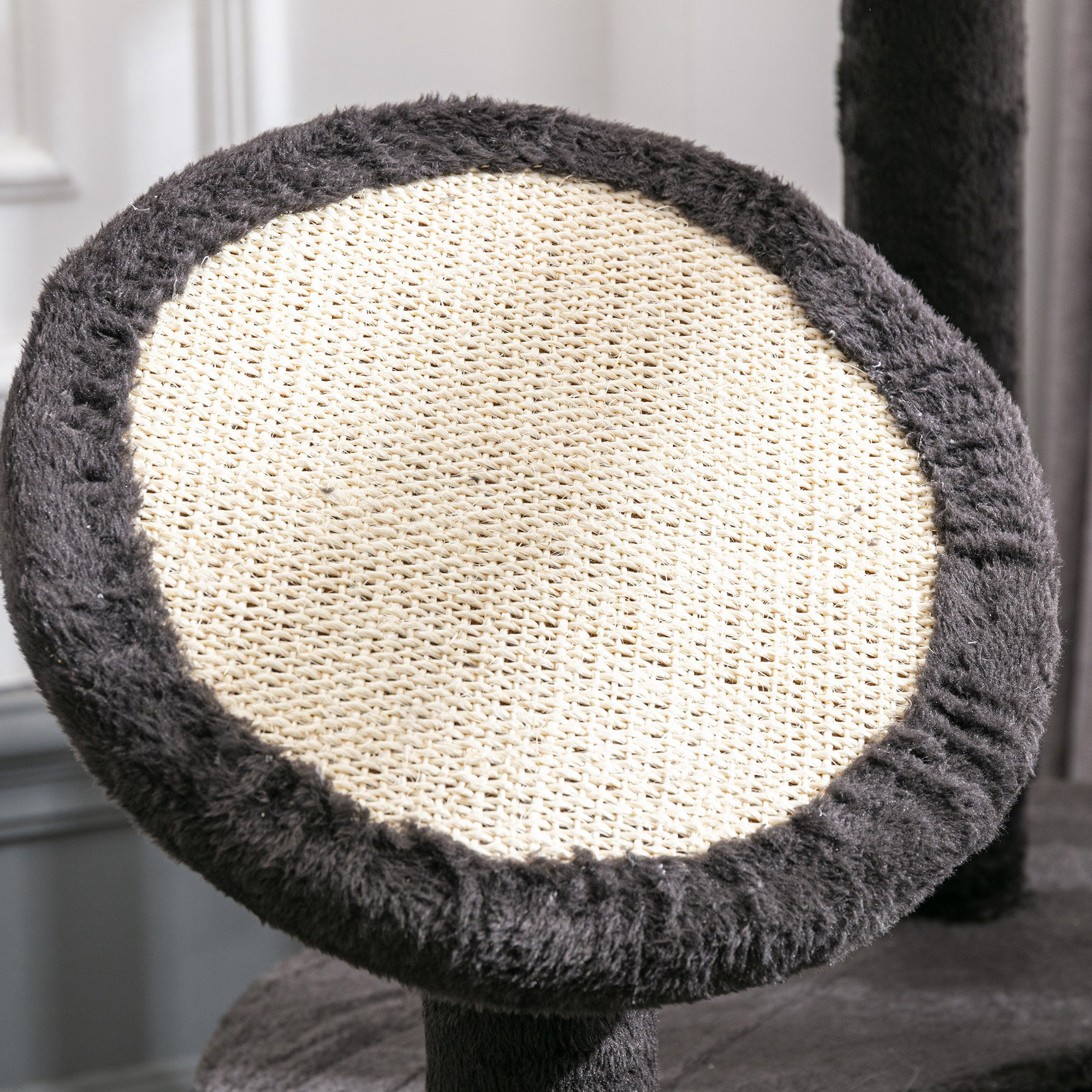 Primer plano de una plataforma de árbol para gatos. La plataforma tiene un borde gris oscuro y una alfombra beige claro.