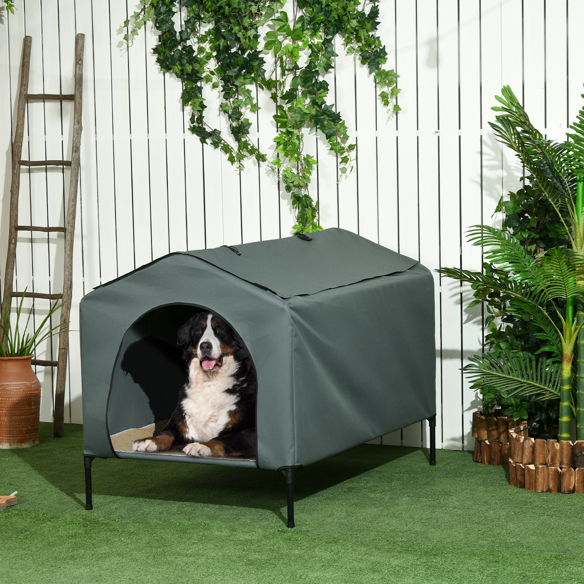Casa para perros con un Boyero de Berna dentro. La casa es verde con un fondo de valla blanca.