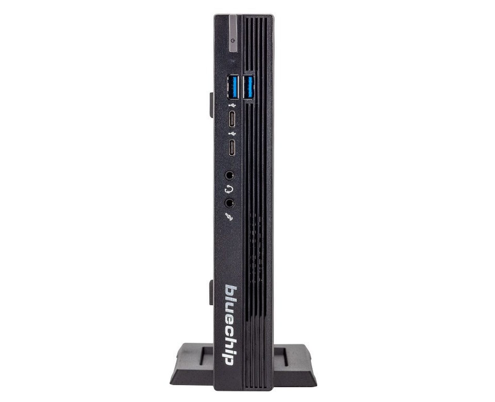 Mini PC nero in posizione verticale, con porte e il logo "bluechip". È su un supporto.