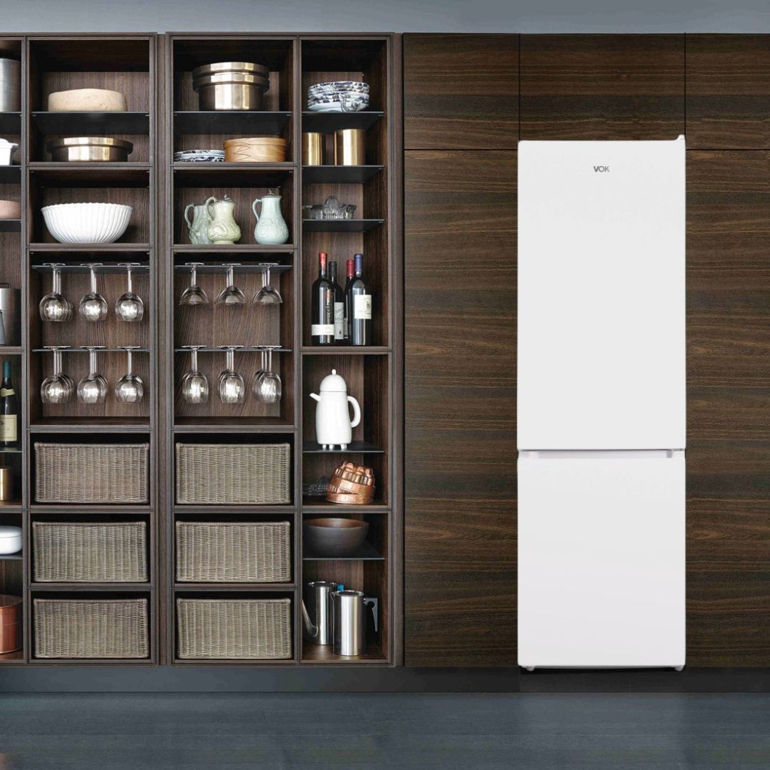 Refrigerador VOX blanco con un gabinete de paneles de madera oscura que contiene vasos, botellas de vino y cestas.