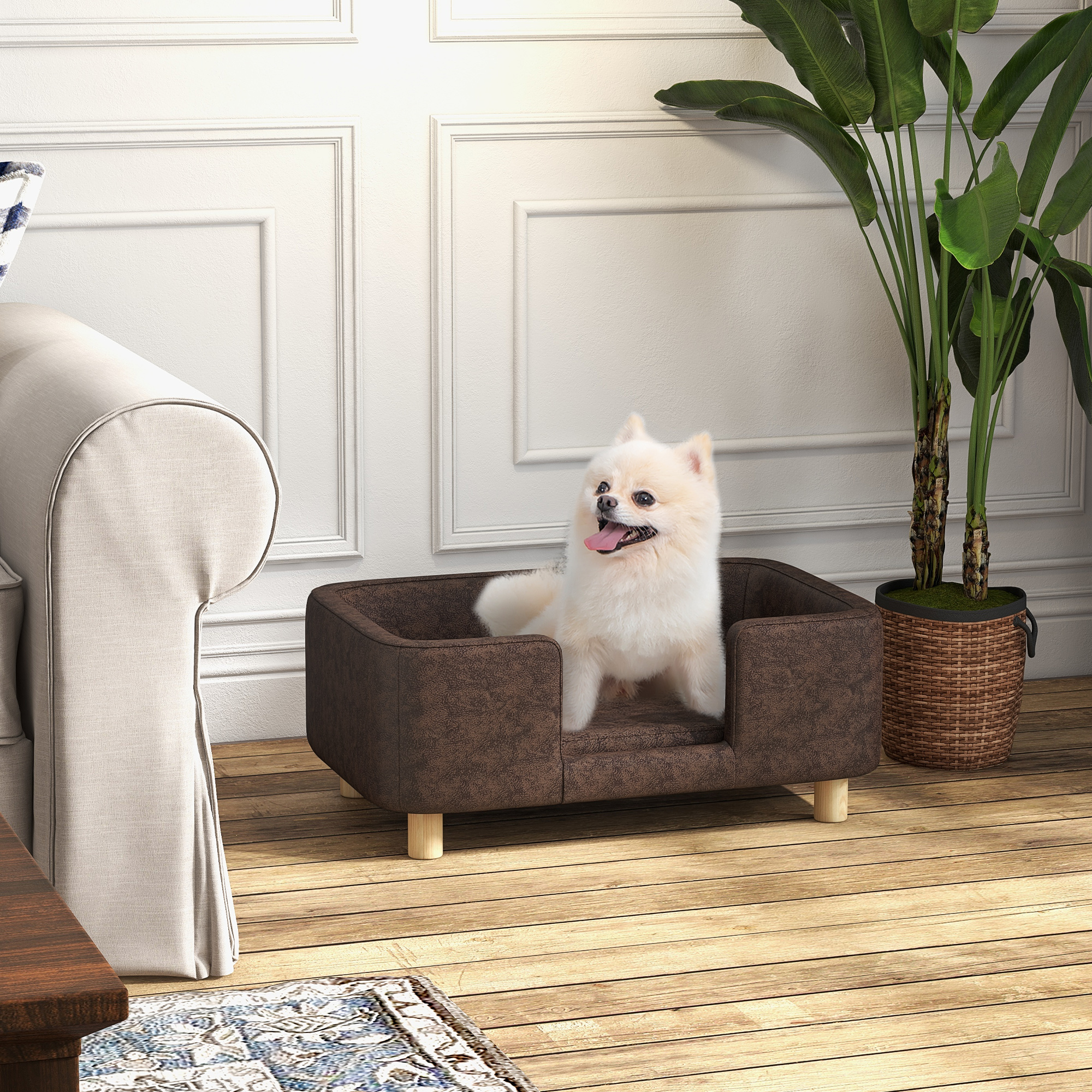 Un perro en una cama marrón con patas de madera, en una habitación con sofá, alfombra y planta.