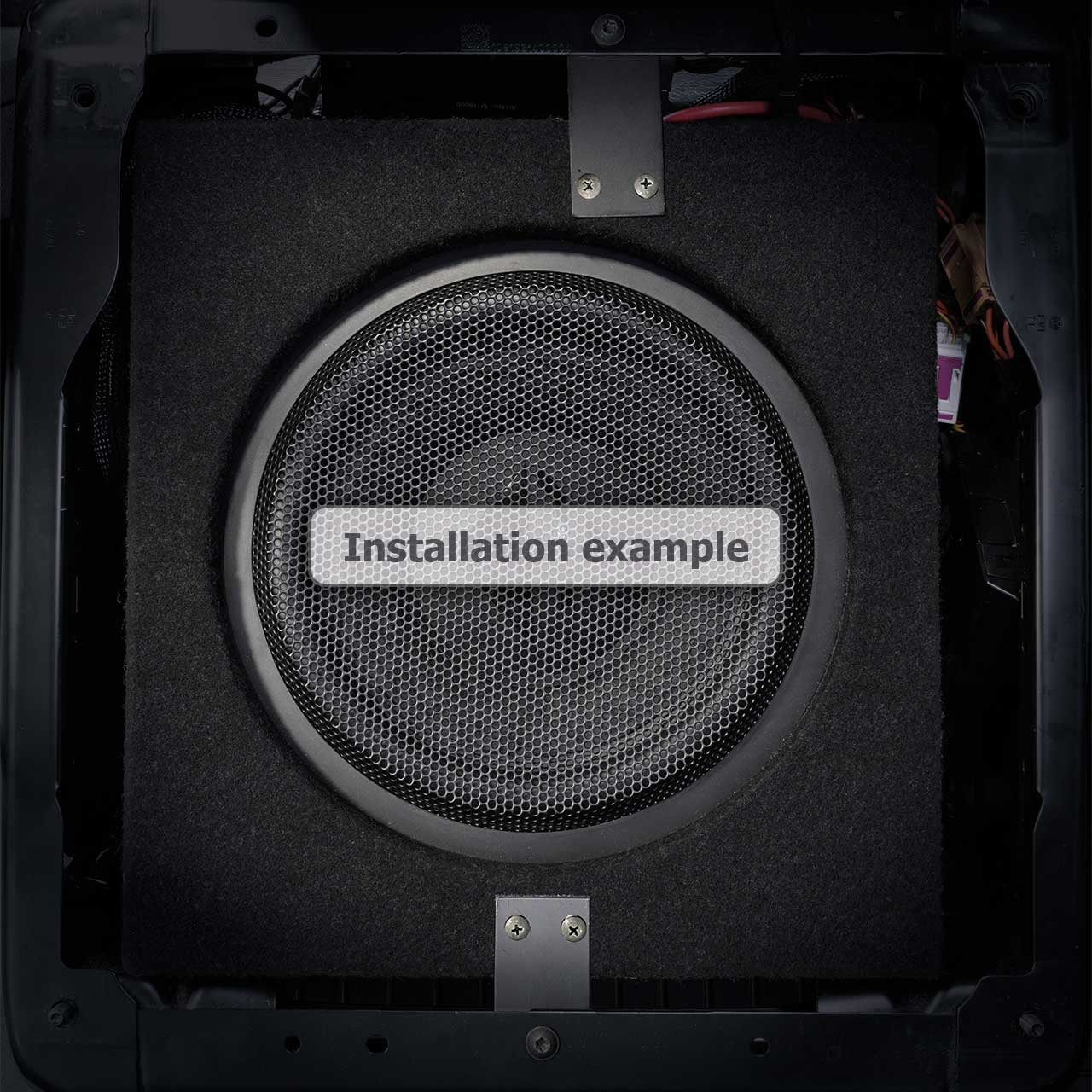 Ein Subwoofer-Lautsprecher mit einem Mesh-Cover und einem weißen Text "Installation example".