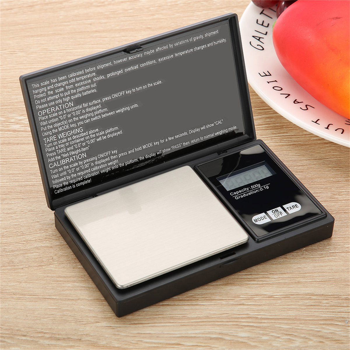 Kleine Digitalwaage mit Anleitung, Knöpfen und einem geöffneten Display.