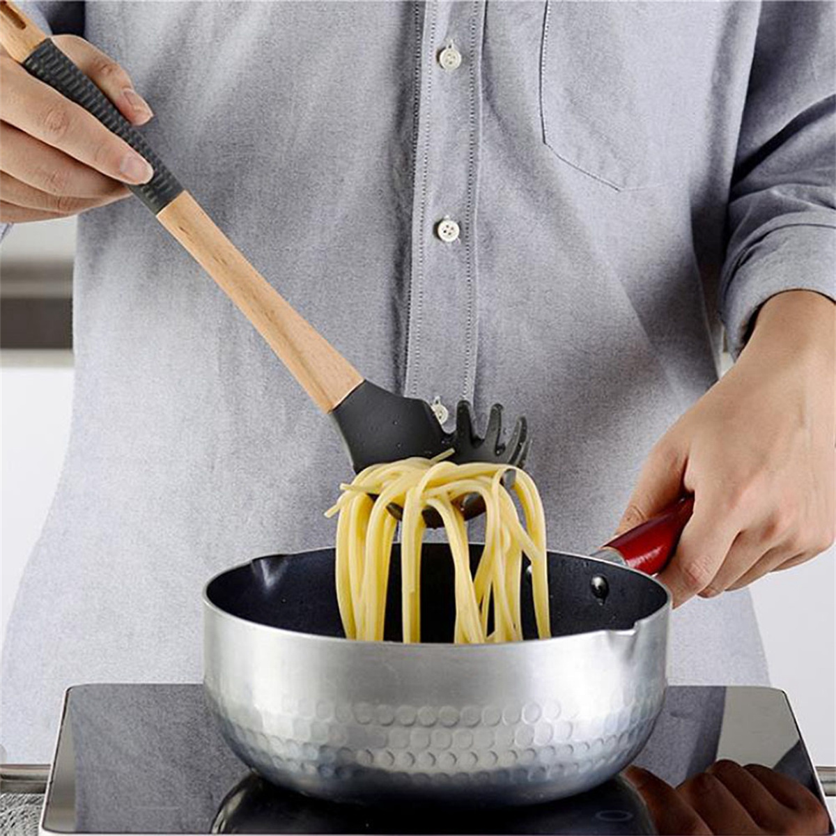 Eine Person hält eine Spaghetti-Gabel und hebt gekochte Spaghetti aus einem Topf.