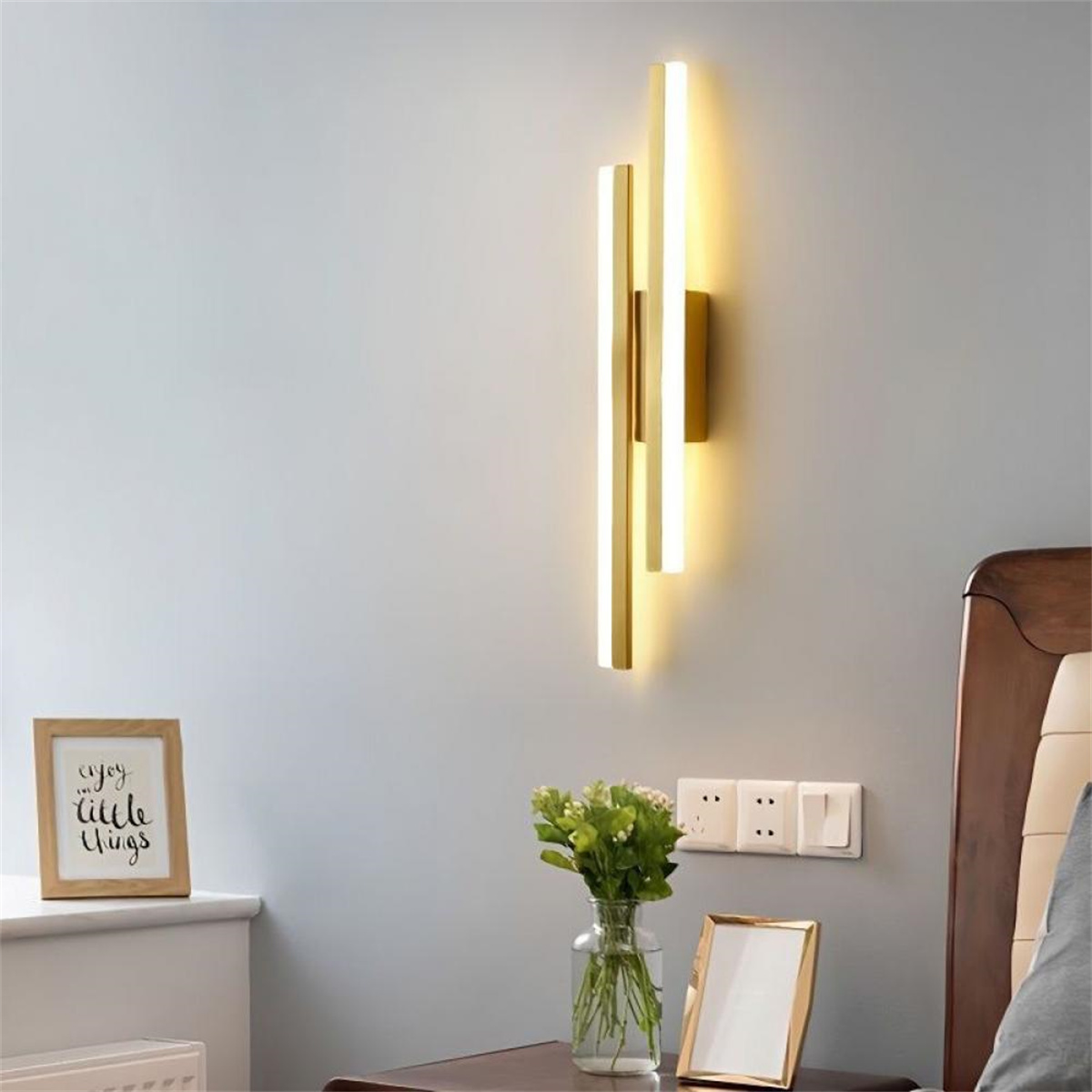 Moderne Wandleuchte mit zwei vertikalen goldenen Linien, mit hellgrauer Wand.