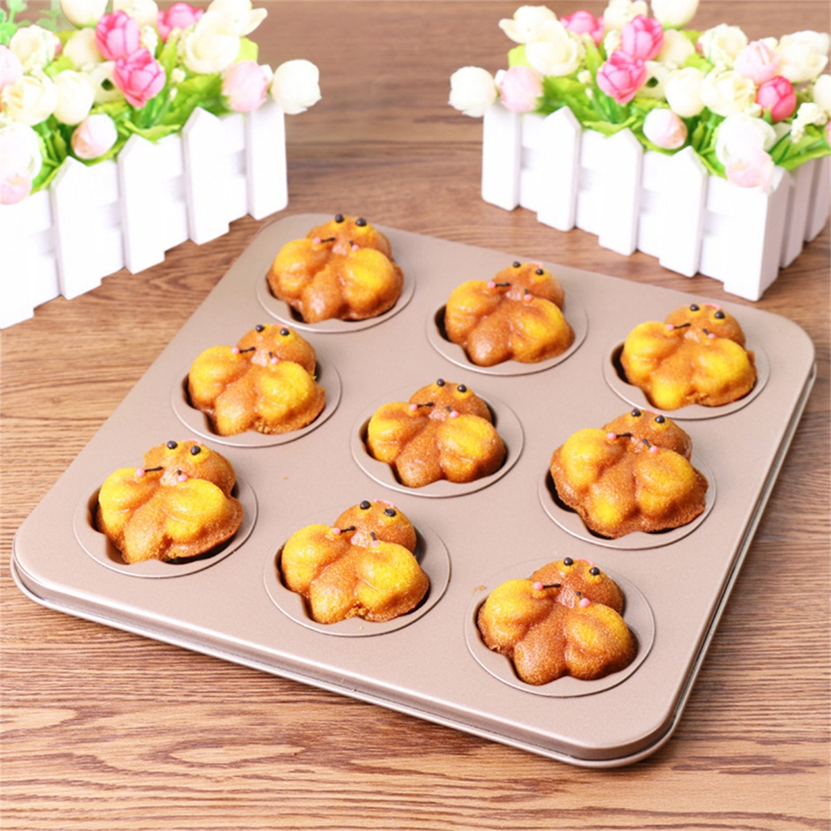 Muffinform mit neun gebackenen, blütenförmigen Muffins in einer Küche.