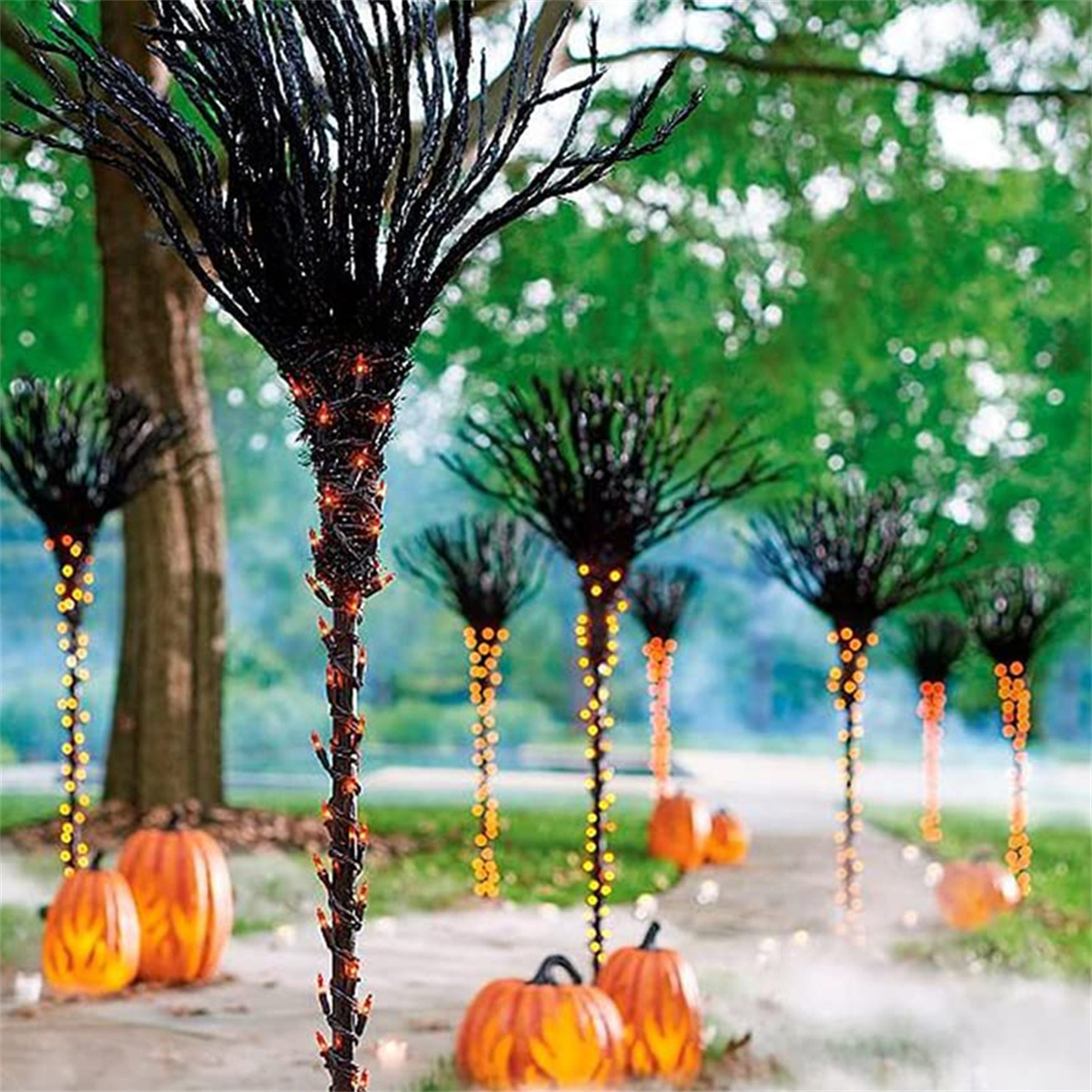Halloween-Dekorationen. Schwarze Äste mit Lichtern, Kürbissen und einem Pfad.