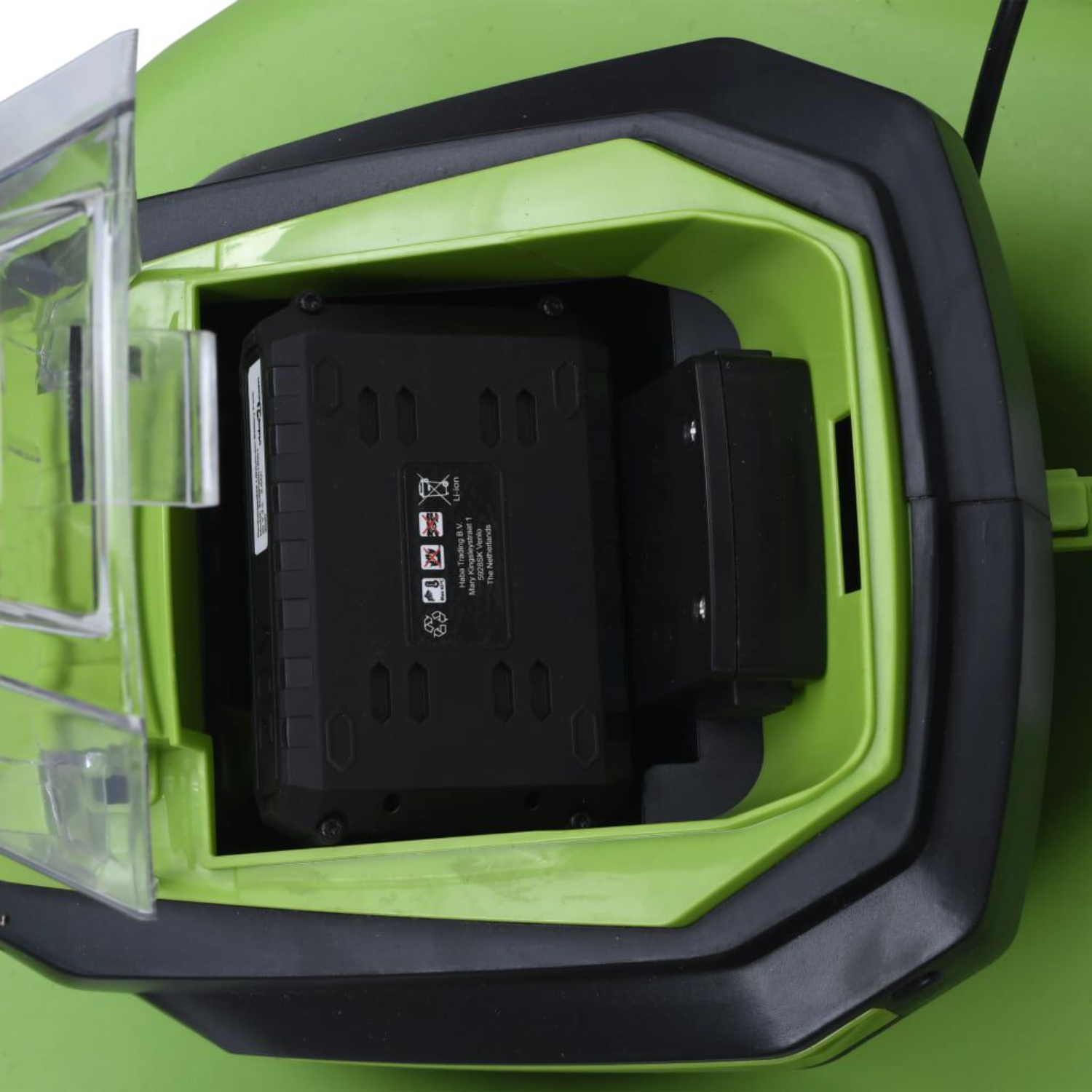 Ein offenes grünes Fach, das schwarze Batterien in einem limettengrünen, geschlossenen Raum mit durchsichtigem Deckel zeigt.