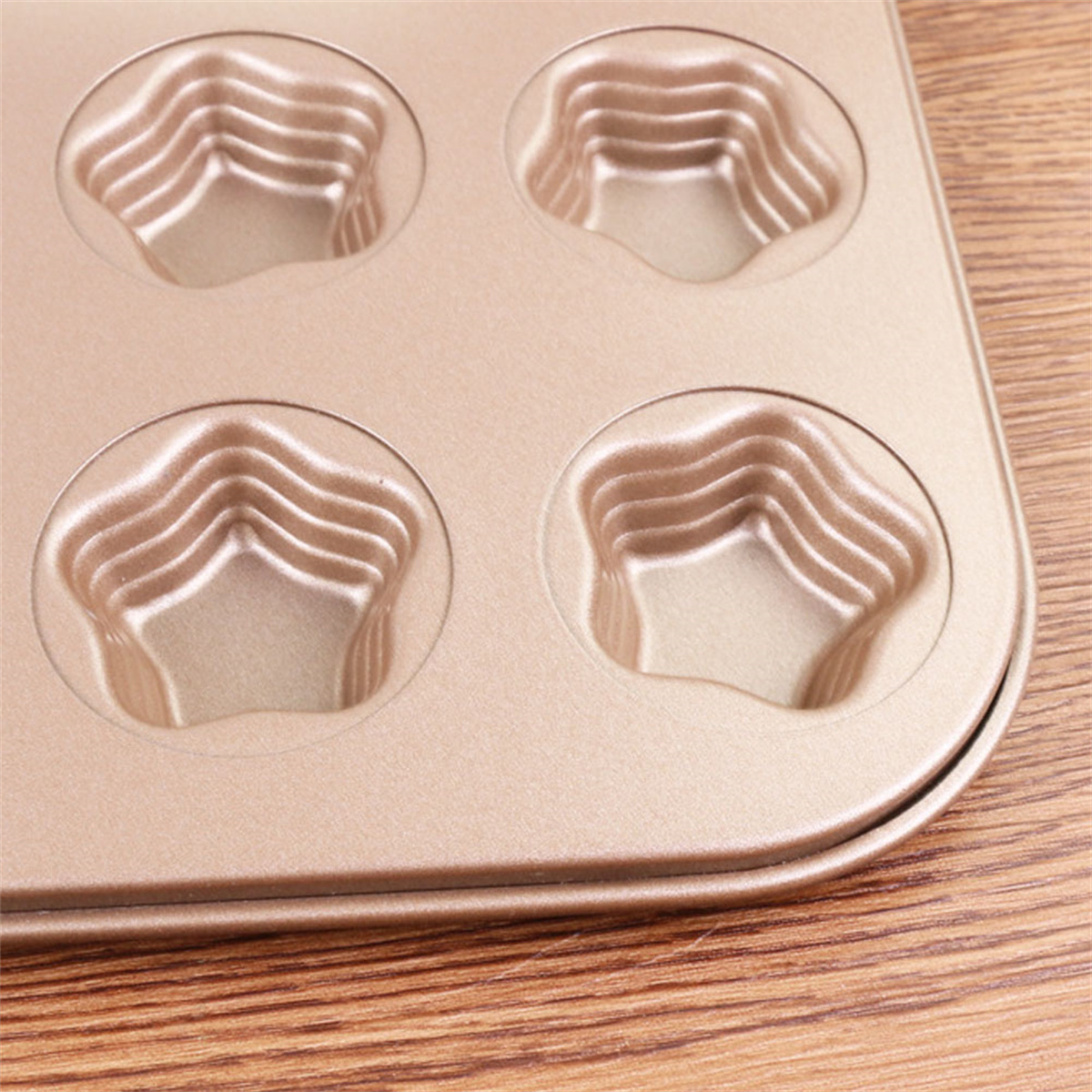 Nahaufnahme einer goldfarbenen Backform mit sternförmigen Formen für Muffins oder Cupcakes.