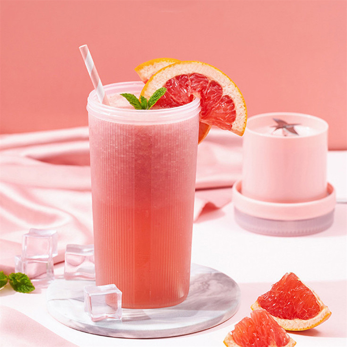 Ein rosa Getränk in einem hohen Glas mit Strohhalm, Grapefruitscheibe und einem kleinen Mixer.