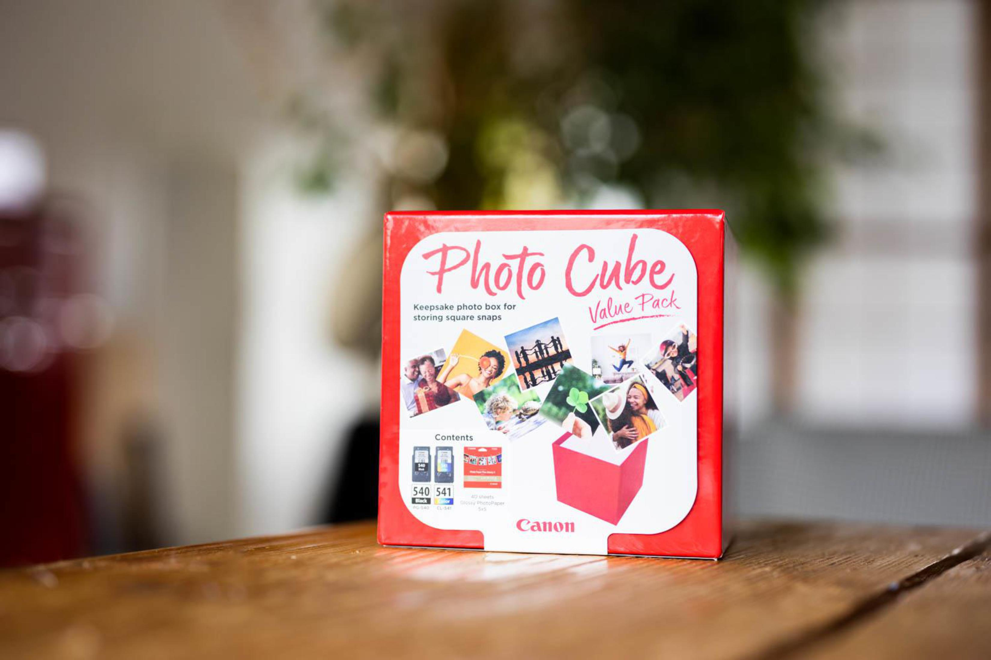 Photo Cube box on a table with out-of-focus background of a room and a wooden table.