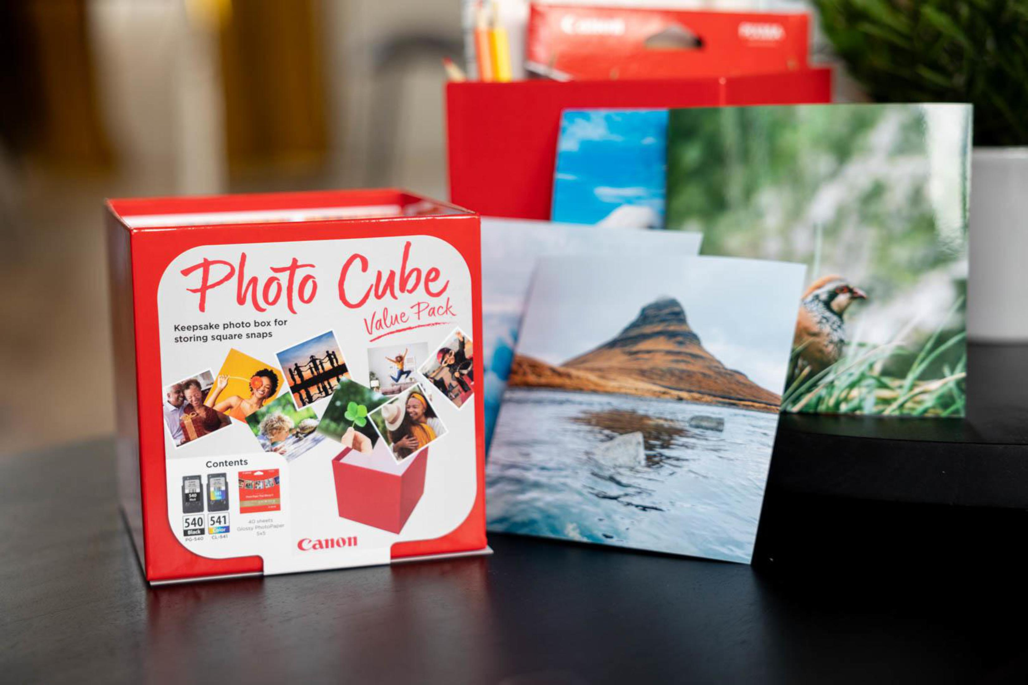 Photo Cube box and photos on a table. Photos of a mountain, people, and a bird are visible.