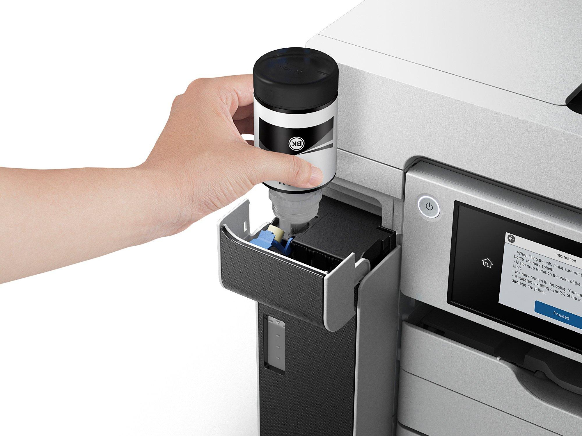 Ręka wlewa czarny tusz z butelki do gniazda tuszu w drukarce.