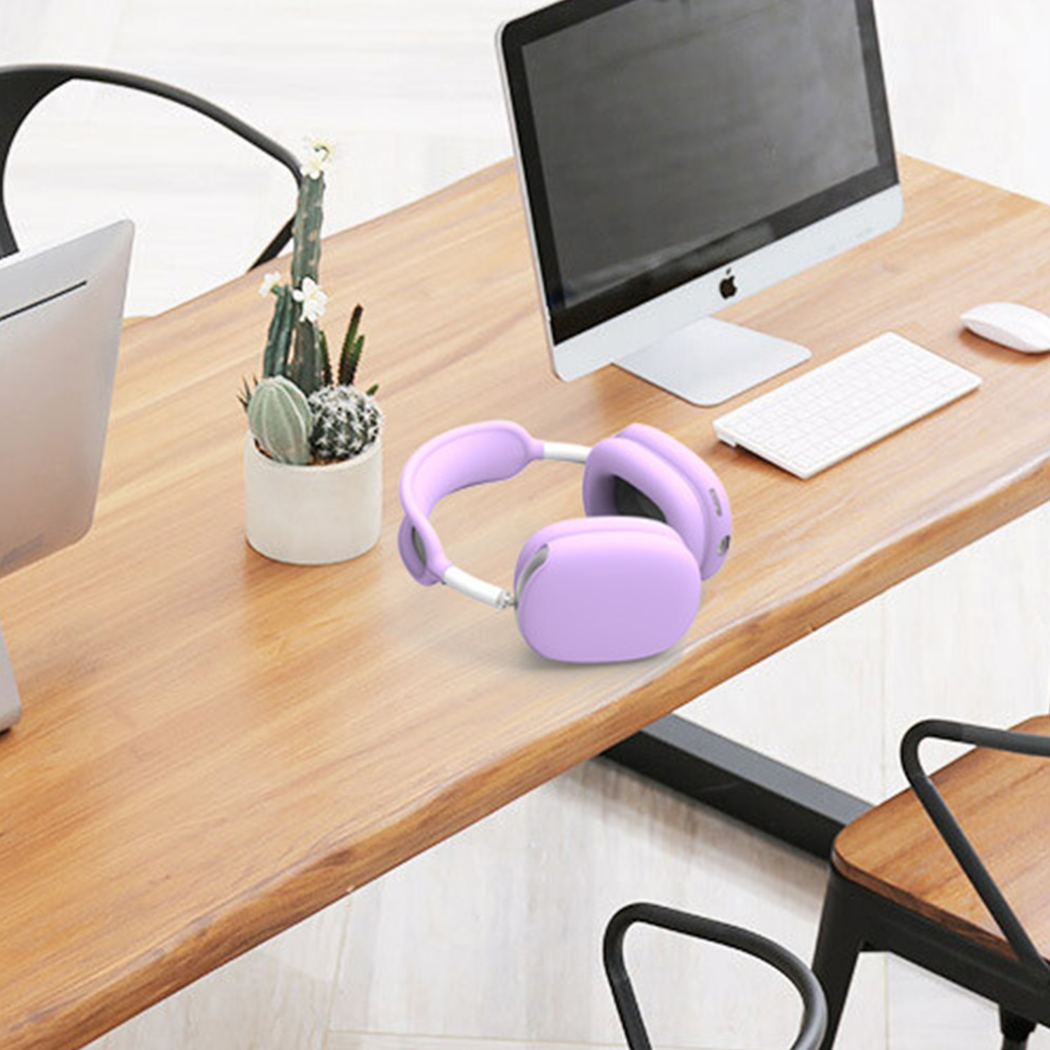 Para fioletowych słuchawek na drewnianym biurku w pobliżu komputera i rośliny.