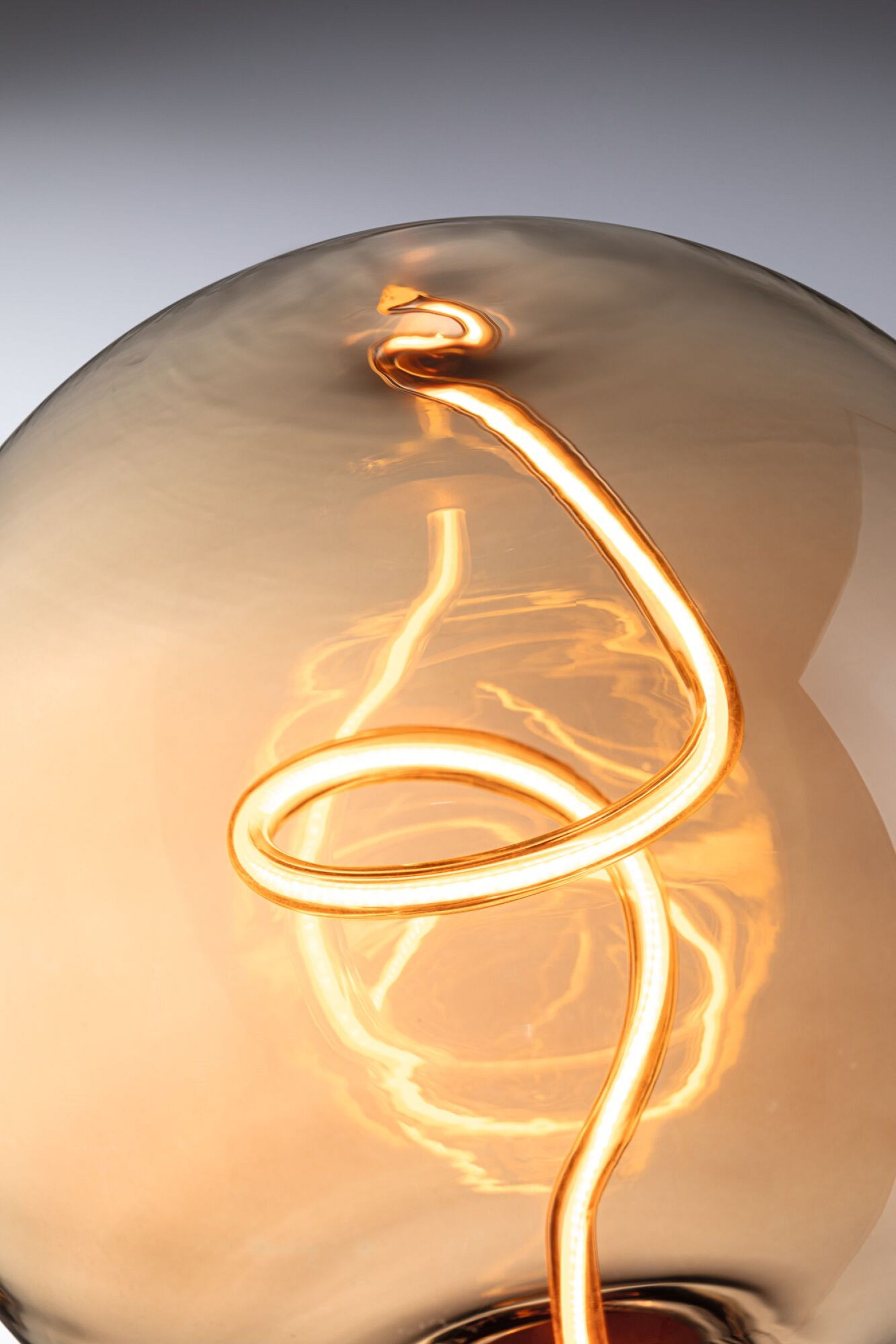 Zbliżenie żarówki z żarzącym się włóknem, na rozmytym tle.