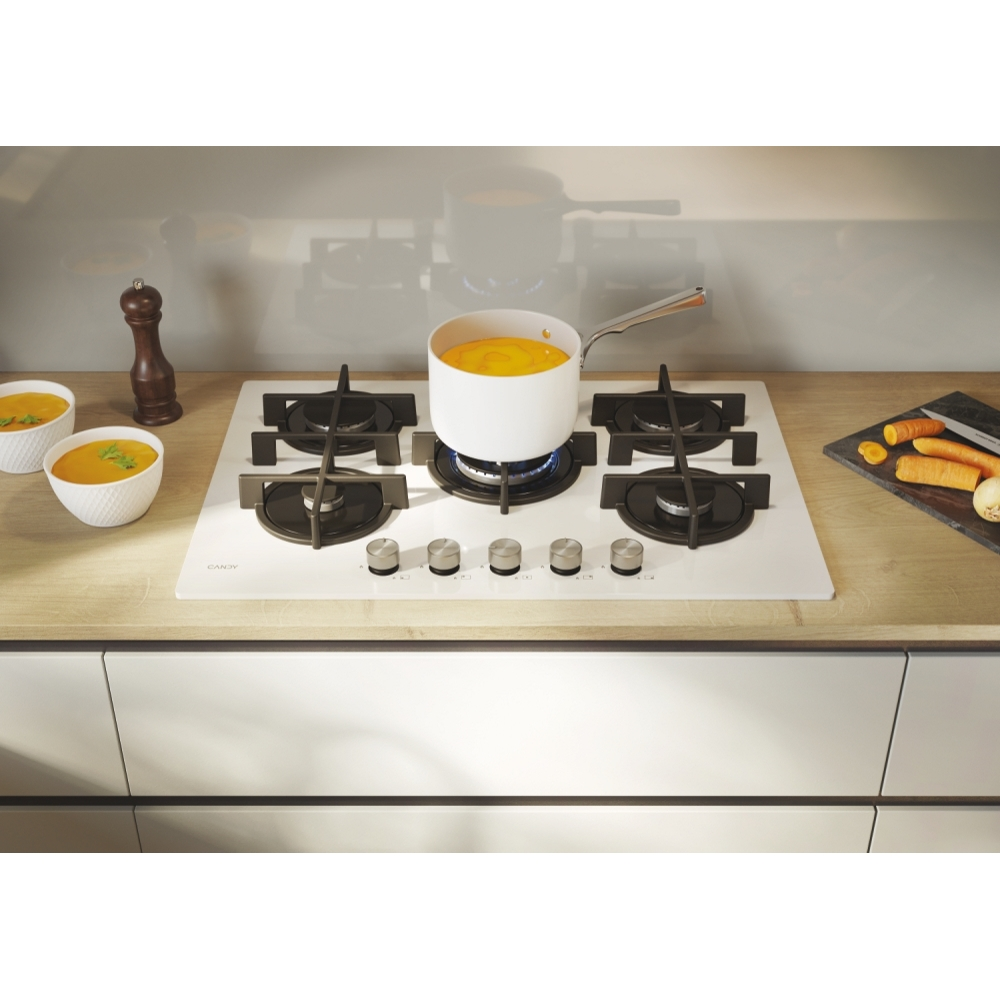 Biała płyta kuchenna z garnkiem do gotowania i miskami z zupą.