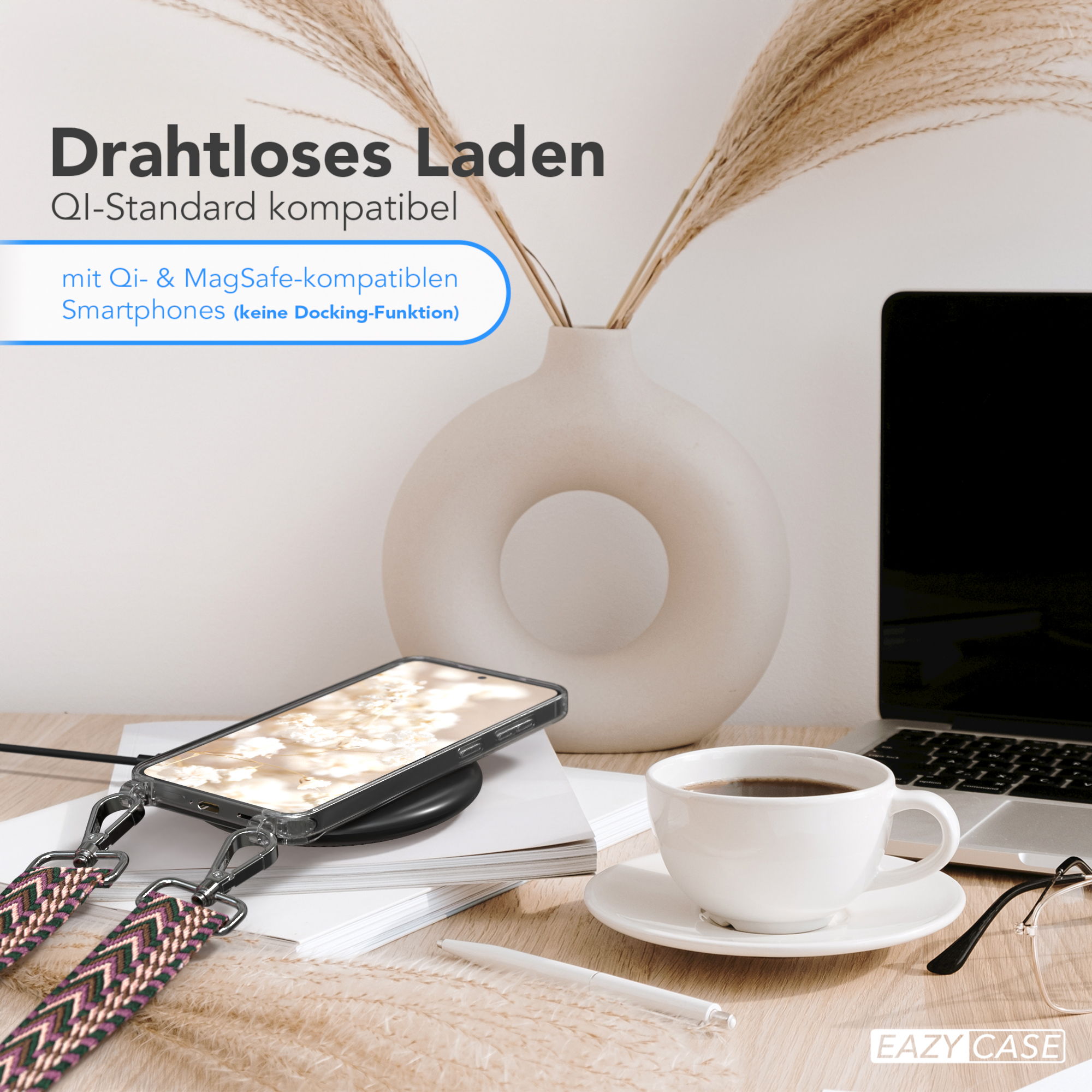 Ein Telefon liegt auf einem kabellosen Ladegerät. Eine Kaffeetasse, ein Stift und ein Laptop stehen auf dem Tisch.