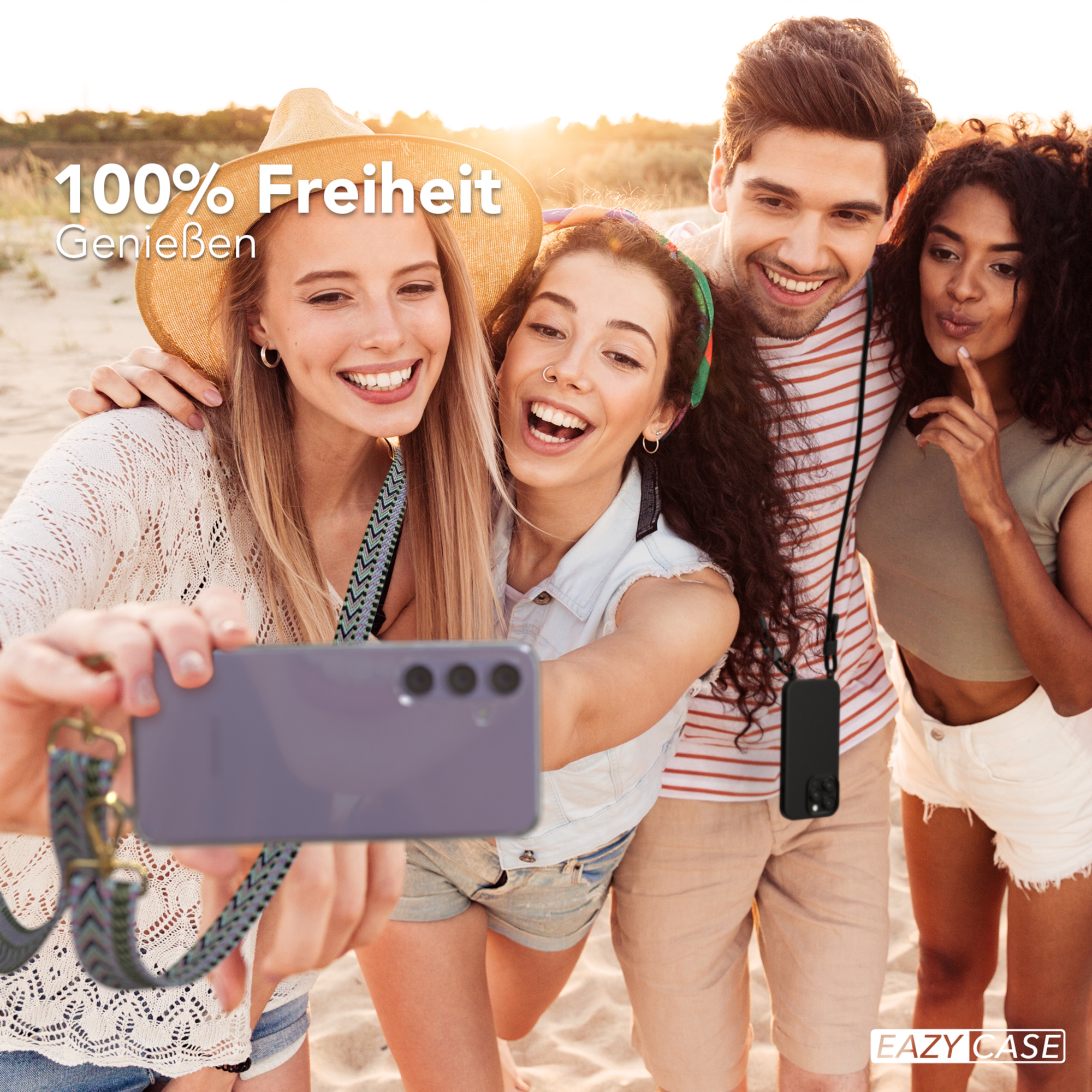 Vier lächelnde Personen machen ein Selfie am Strand. Eine Person hält das Telefon mit einem Lanyard.