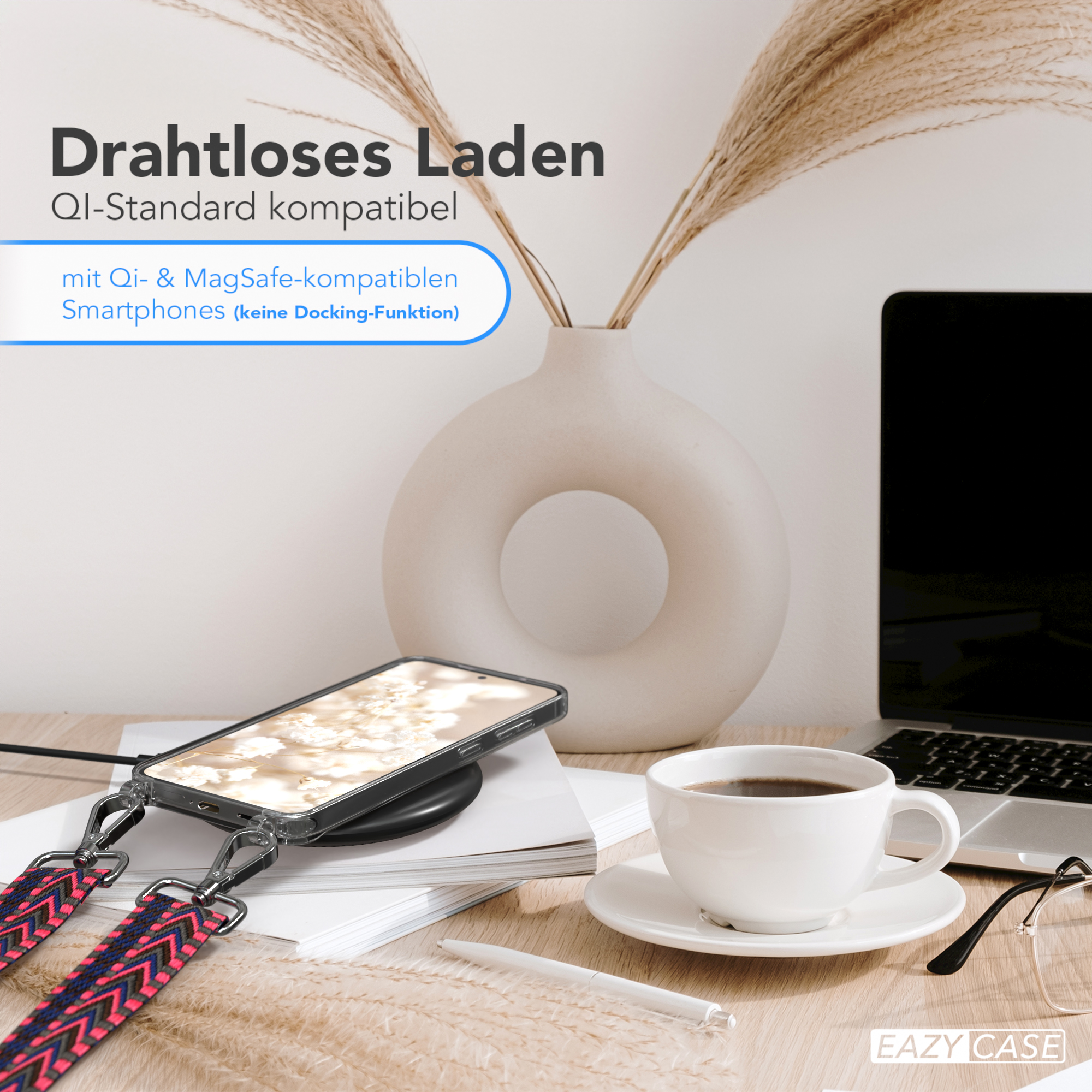 Telefon auf Ladegerät, Kaffee, Laptop, Brille und Vase mit Pflanzen auf einem Holzschreibtisch.